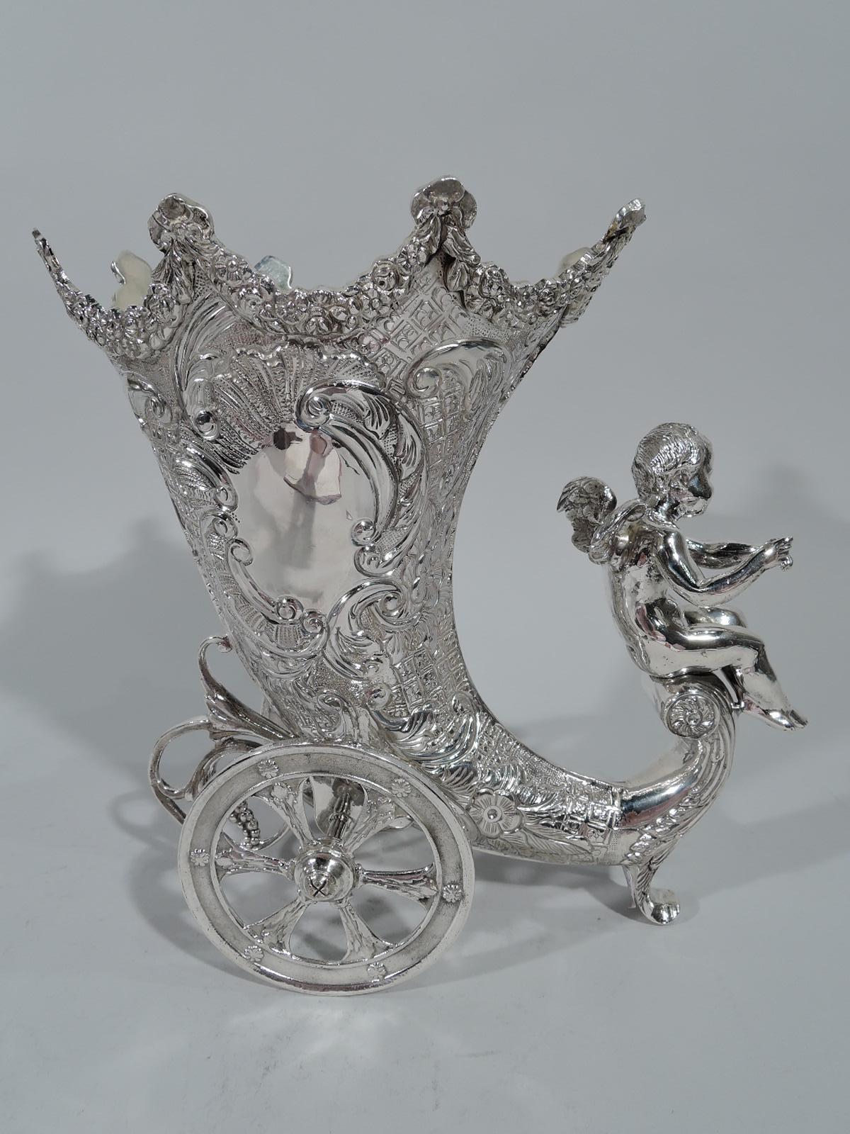 German Rococo revival sterling silver centerpiece vase, circa 1950. Cornucopia with garlanded rim and rising volute scroll base. Axel-mounted with rotating wheels. Tolled and chased, flowers, leafy scrolls, and diaper, and stippling. Asymmetrical