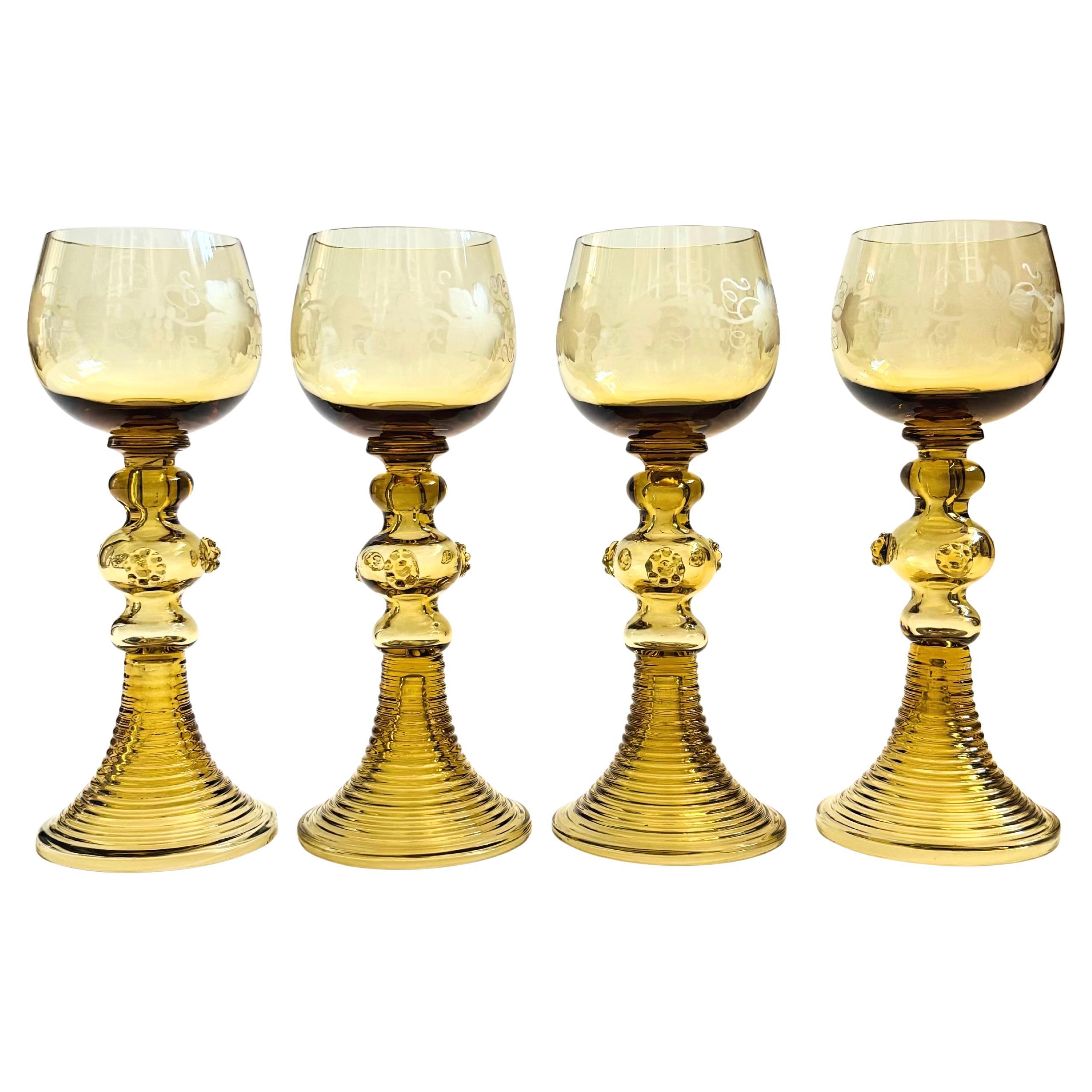 A set of 4 antique German roemer glasses. Clear glass bowls with an etched grape leaf design. Beautiful ribbed bases with blown glass detailing. Color is a muted ochre.

