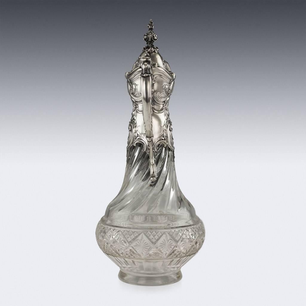 Antique 19th century German solid silver and cut glass extremely decorative wine claret jug, of massive size, cut-glass body mounted with a silver collar profusely chased in the Rococo style, with scrolling foliage and flowers, scroll handle, parcel