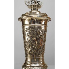 German silver plate chalice with floral relief and bicycle rider finial on lid