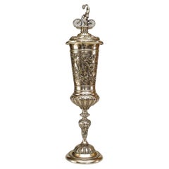 German silver plate chalice with floral relief and bicycle rider finial on lid