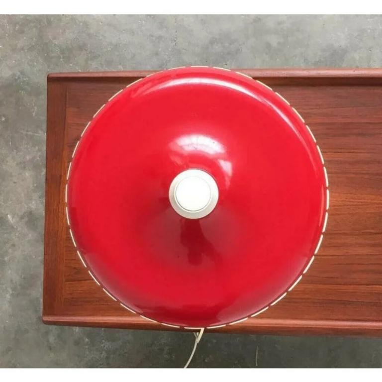Un classique du design des années 1970. Une lampe de table de la collection Siemens. Voici la version avec un couvercle rouge en métal et un anneau en plastique nervuré servant de diffuseur. Le parapluie a la forme classique d'un ovni. Il est divisé