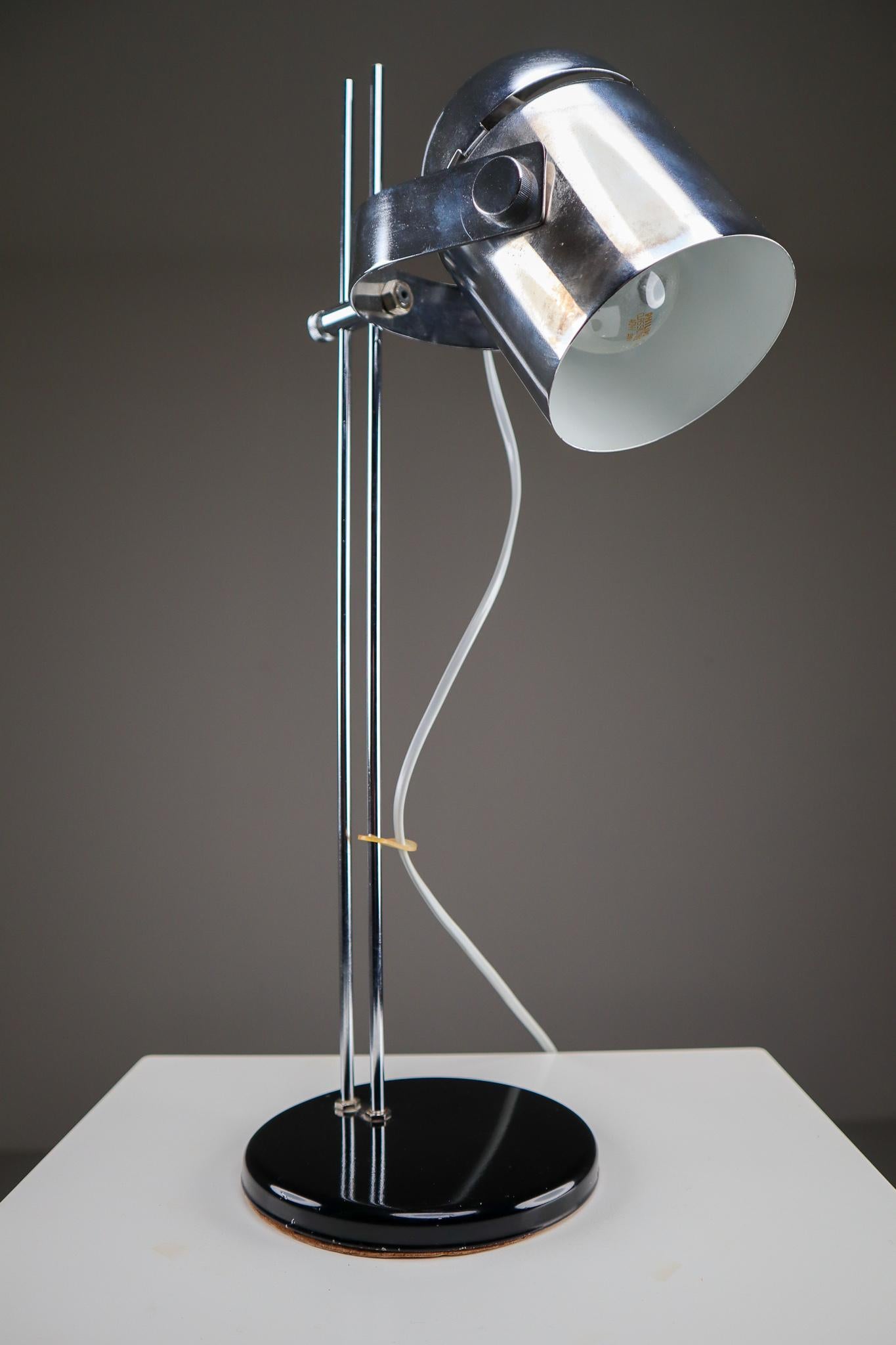 A German adjustable height desk lamp, with cylindrical polish steel shade on a chromed metal post with circular black metal base. The shade can be moved up and down the post to the desired height and the shade can be easily angled to a wide range of