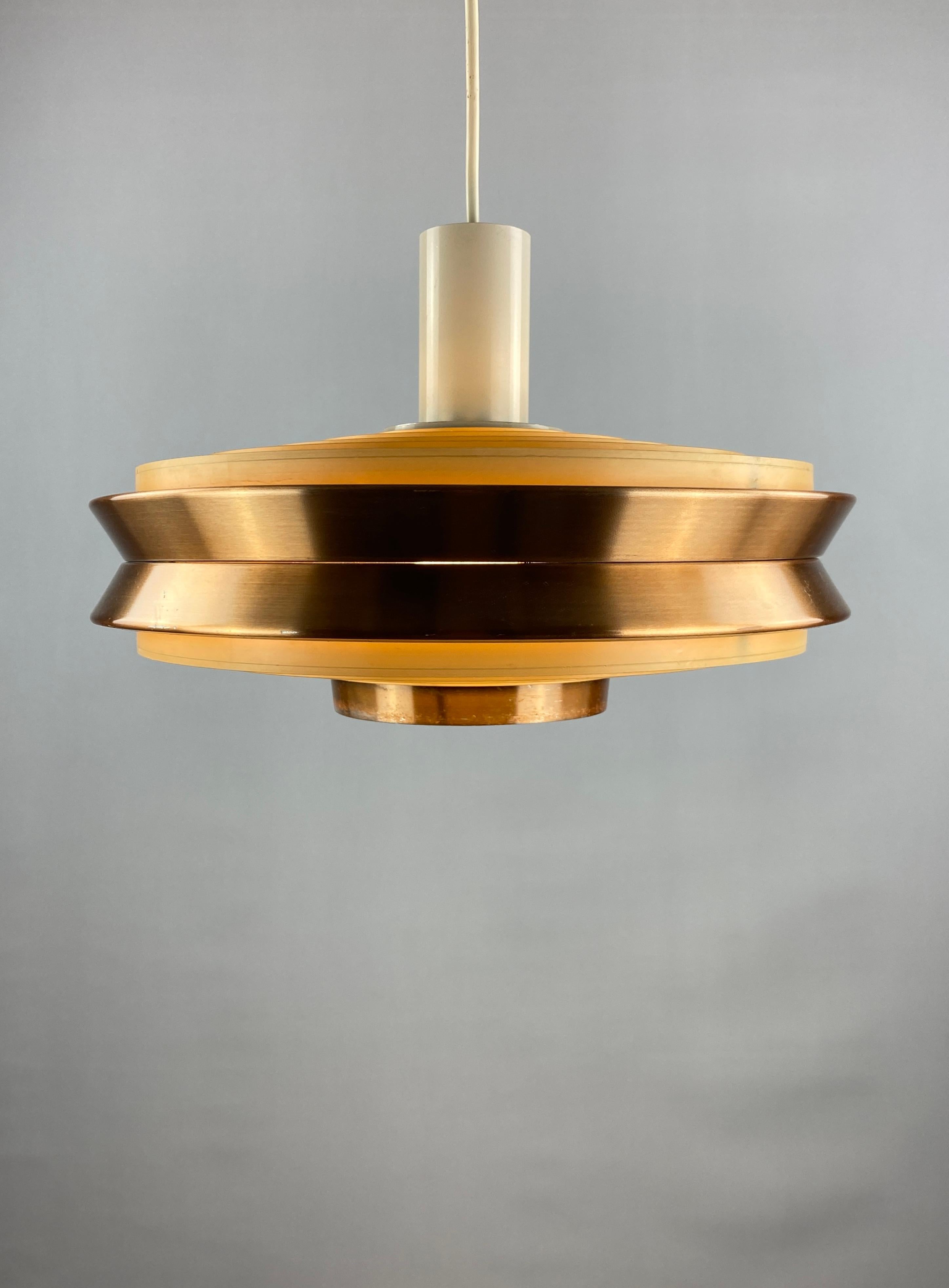 Elegant UFO shaped pendant lamp designed by VEB Metalldrücker Halle from the DDR, East Germany in the 1970's. Made by metal and copper colored metal, the diffuser is made of plastic.

Provides very warm light through the
