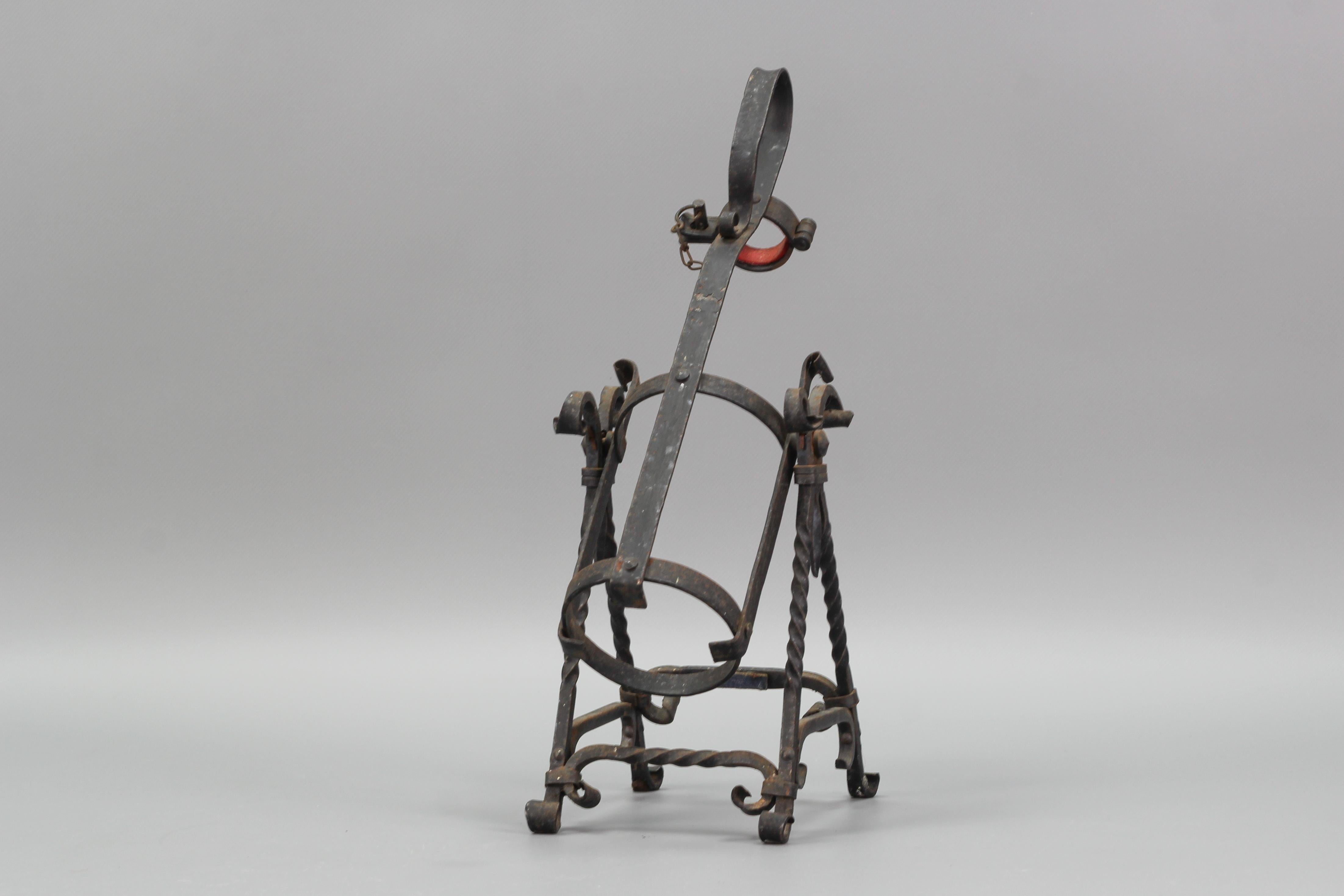 This beautiful bottle holder/bottle pourer in Medieval style was made in Germany circa the 1970s by the company Asbach. The wrought iron stand holds a bottle and can be also used for the purpose of pouring brandy or other beverages to ensure a
