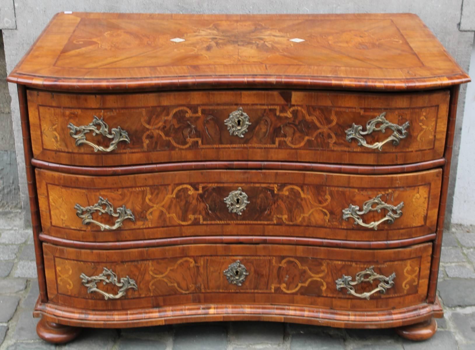 German walnut 18th century chest of drawers.
General curved look. Curved only on the face, the sides are rights. Included of three drawers, all have a frame in marquetry and a marquetry pattern. Fixed handles and locks are in gilt bronze, with a