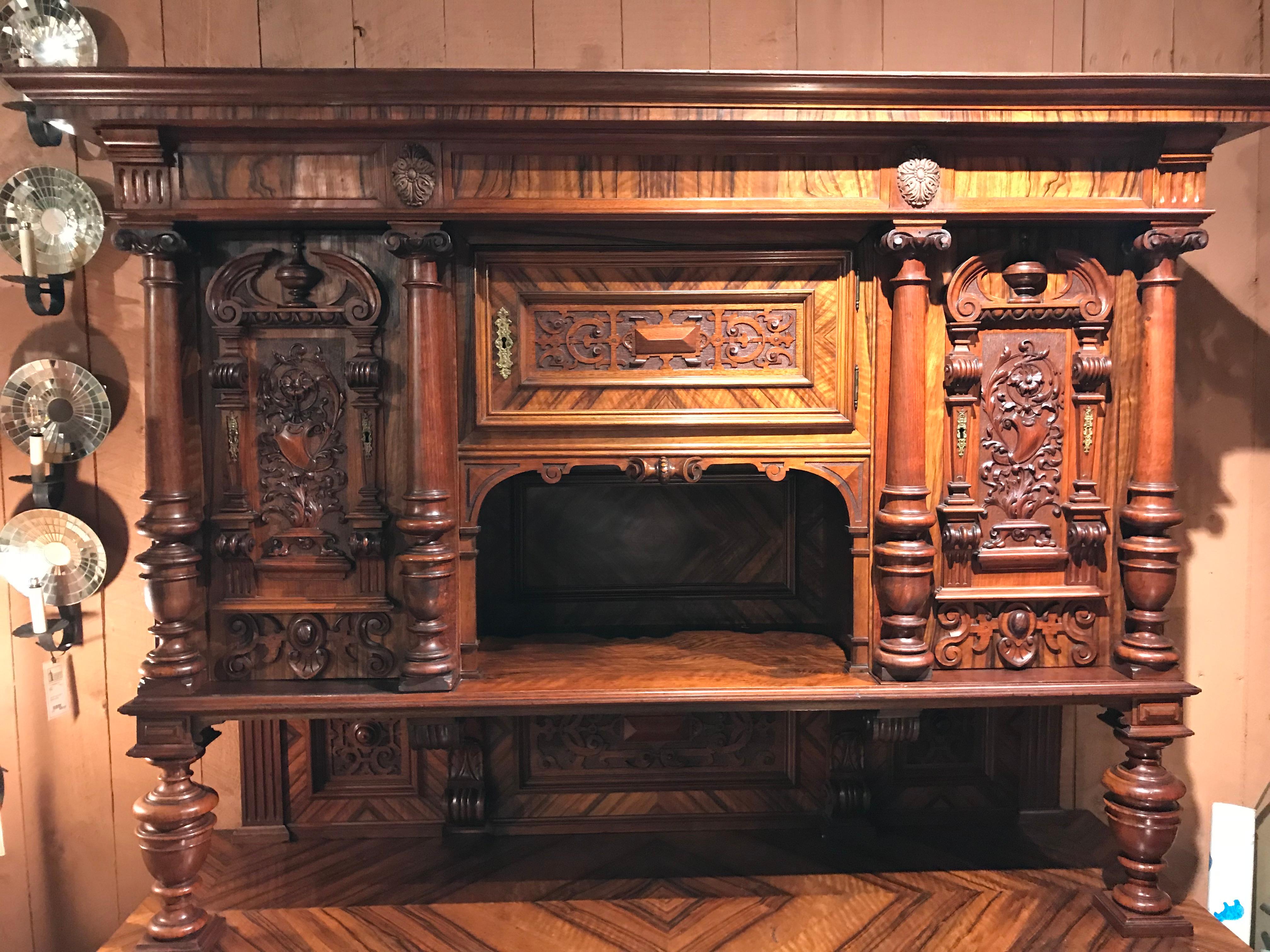 A wonderful two part German walnut schrank or cabinet, its upper case with a molded cornice surmounting a central fitted door and storage compartment, flanked by two boldly carved vertical doors with carved half columns, opening to a two shelf