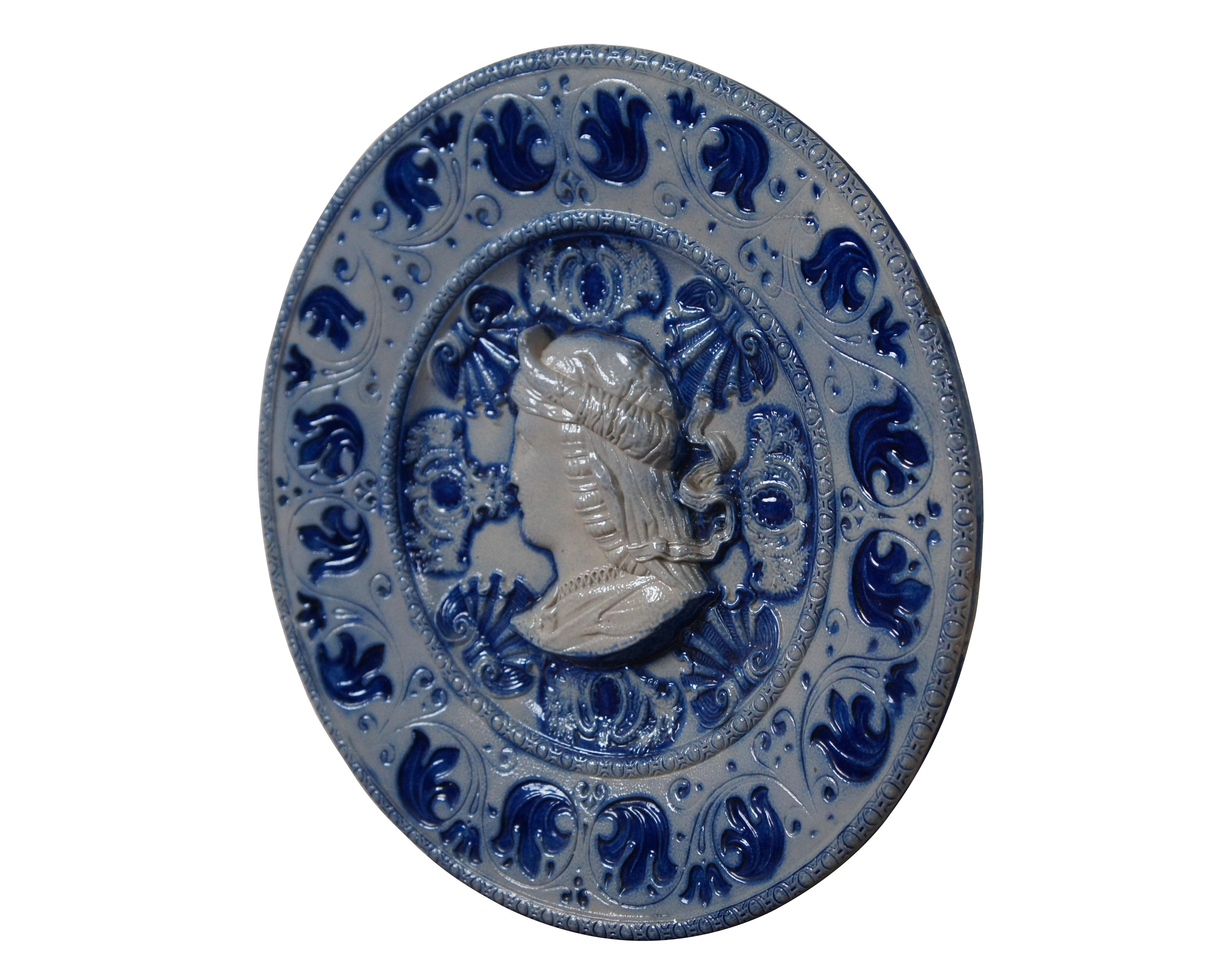 Mid to late 20th century German Westerwald salt glaze and cobalt blue stoneware wall hanging plate / charger featuring a regal looking bust in silhouette, surroundded by scallops and flourishes, within a border of swirling leaves. Marked 145 on