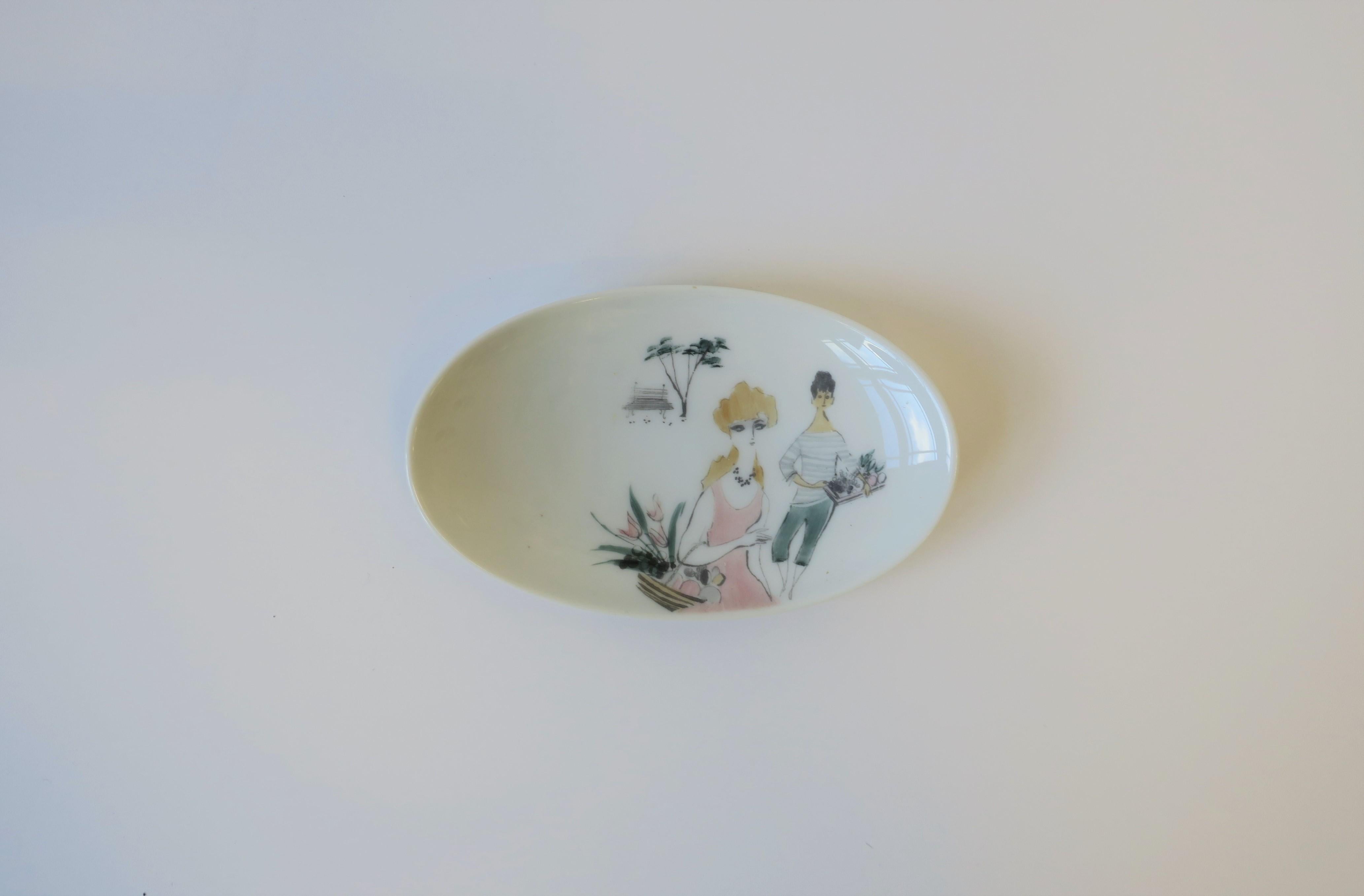 A beautiful German oval white porcelain jewelry dish with female(s) figurative design, 'Rendezvous', by Rosenthal, circa 20th century, Germany. Dish features hand painted female figures holding baskets filled with flowers and fruit in soft pastel