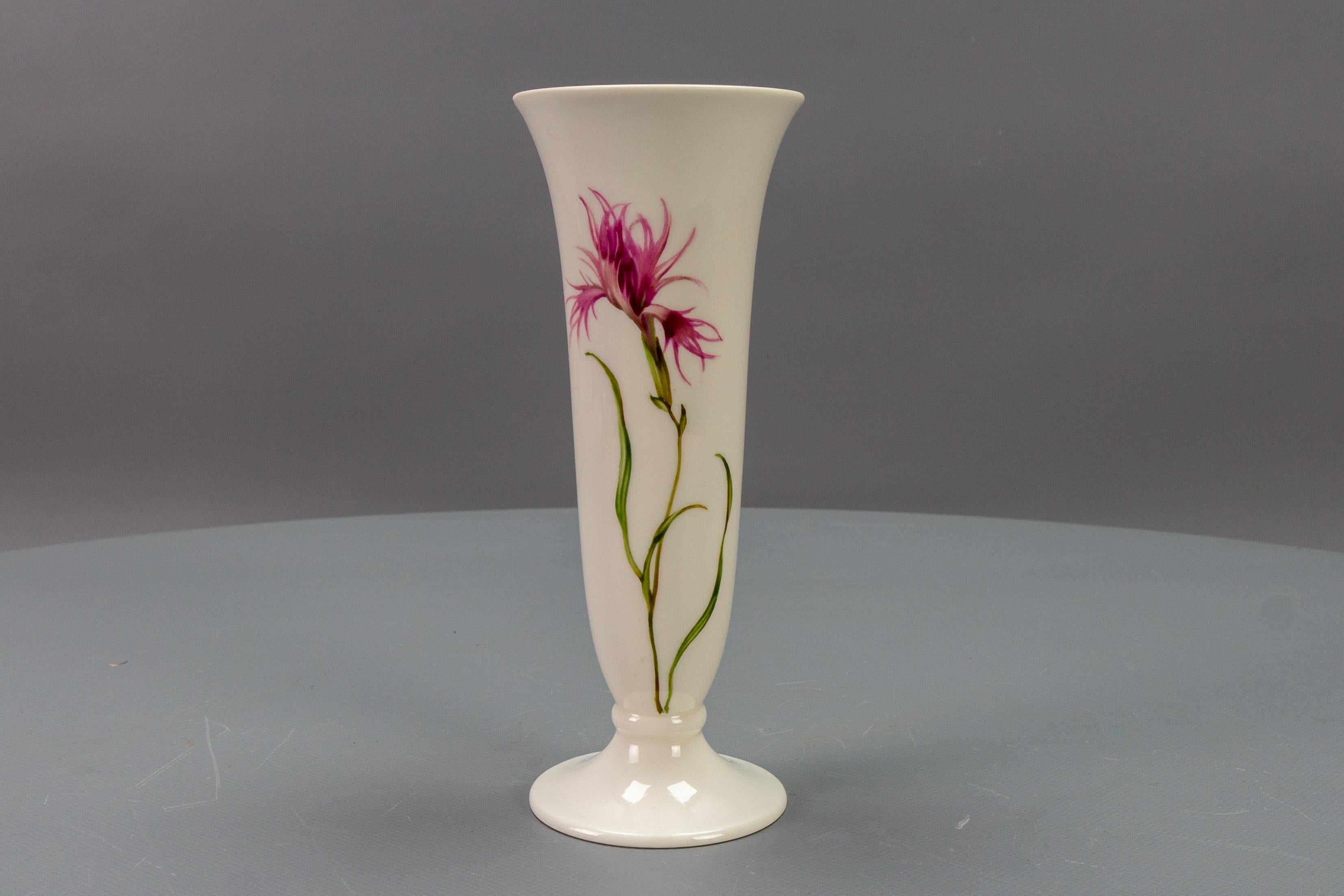This adorable white or light ivory color porcelain vase by Hutschenreuther Selb (LHS) Kunstabteilung (Art Department), Adler Berchtesgaden, features hand-painted flowers - pink feather carnation on two sides - one in a large bud and the other with