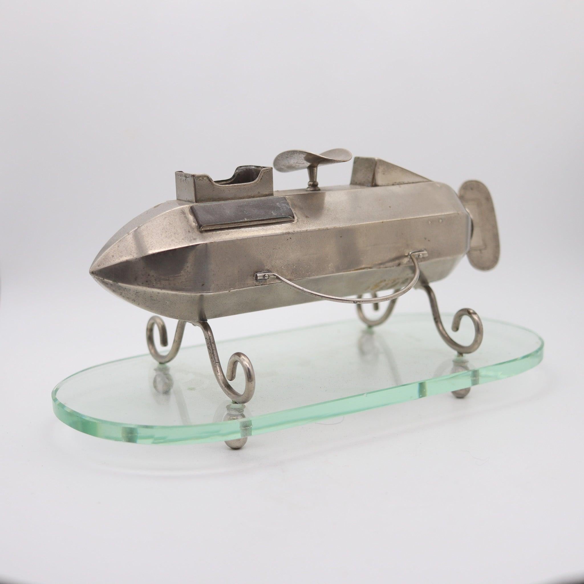 Ein Zigarrenschneider in Form eines Zeppelins im Art-Deco-Stil.

Dies ist eine sehr schwer zugängliche und seltene Schreibtisch Zigarrenschneider und Streichholzschachtel Halter in Deutschland während der Art-Deco-Periode, zurück in 1920. die