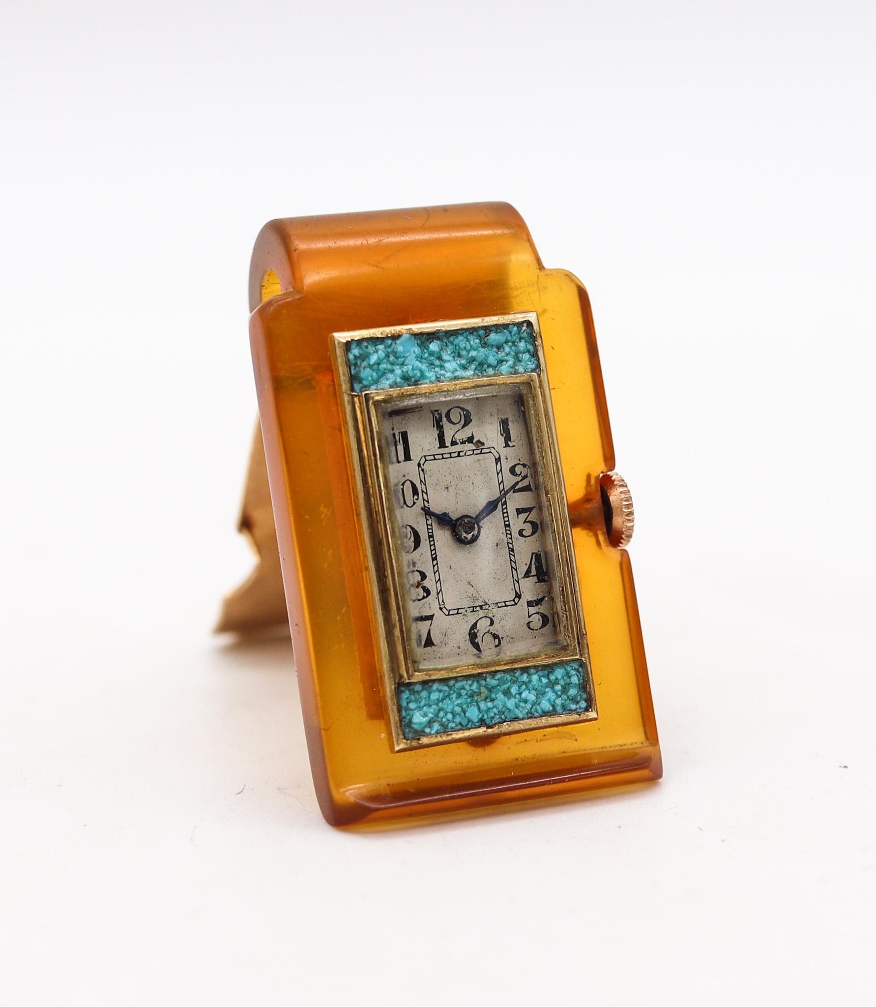 Mechanical money clip with clock.

Fabulous and very unusual piece, created in Europe during the art deco period back in the 1935. This rare money-clip brooch, was most probably made in Germany or Switzerland. It was crafted in Bakelite-Catalin,