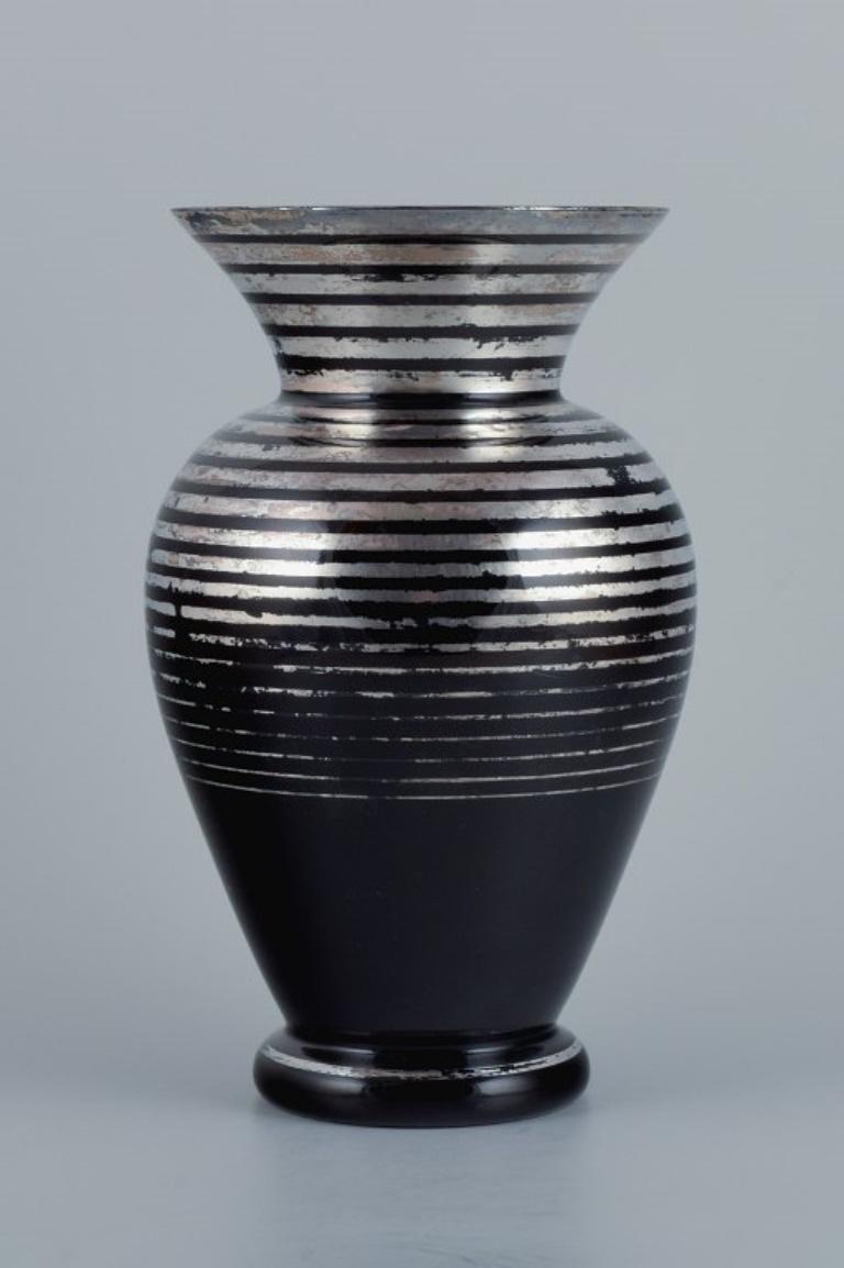 Art Deco glass vase, Germany. With horizontal silver inlays.
1930-1940s.
In excellent condition with minor wear.
Dimensions: D 13,5 x H 24,5 cm.