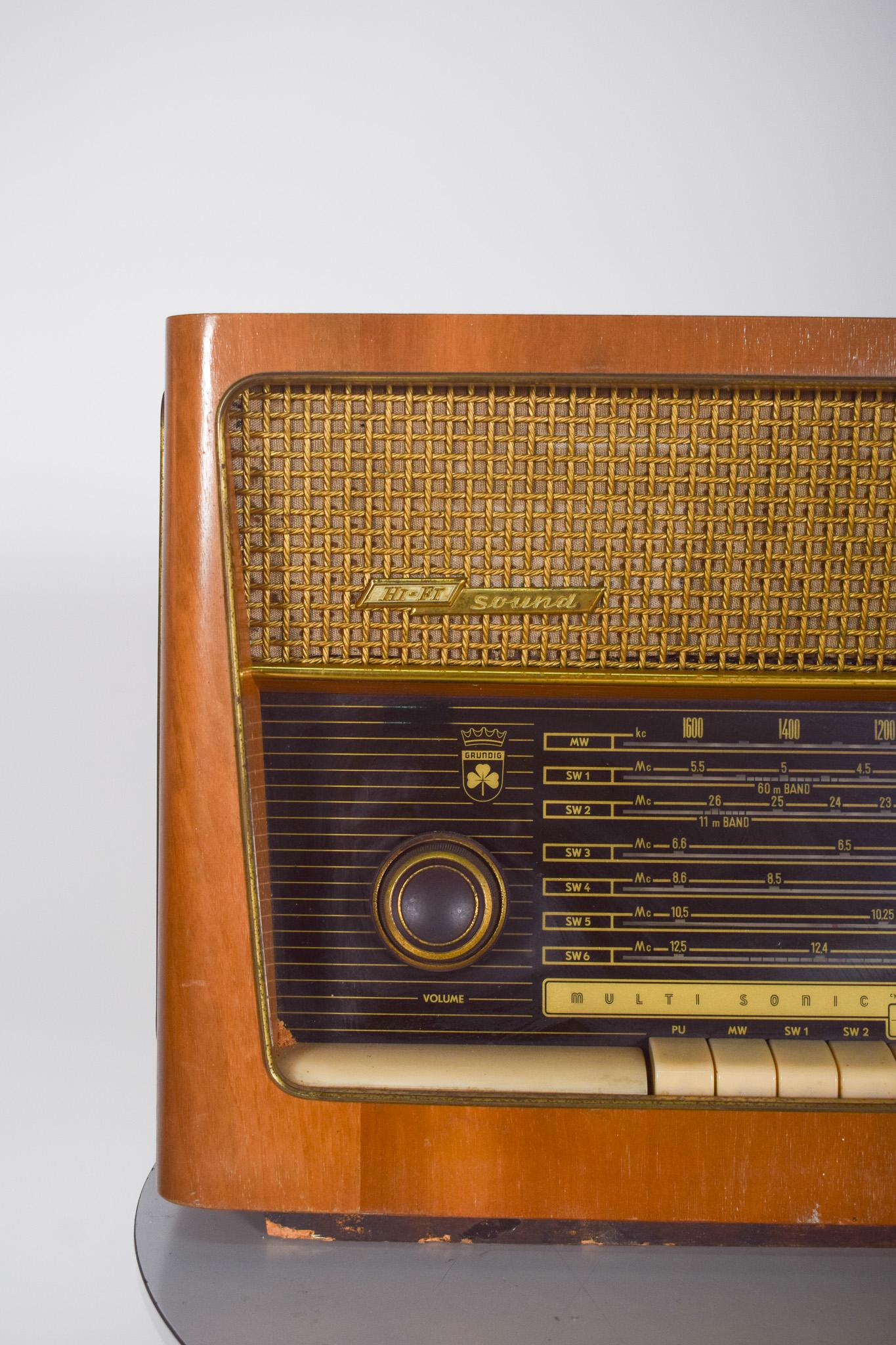 Grundig table radio, Hi Fi Sound. With a varnished wooden case, refined finish and elegant design. The top houses a golden grille that covers the speaker, while the bottom contains the control panel.
The tuning display is large, with detailed