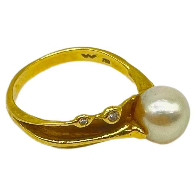 Immerse yourself in the timeless beauty of this exquisite 18k yellow gold ring, a true masterpiece from the distinguished German goldsmithing atelier of Wurzbacher. This captivating ring features a lustrous pearl, elegantly complemented by two
