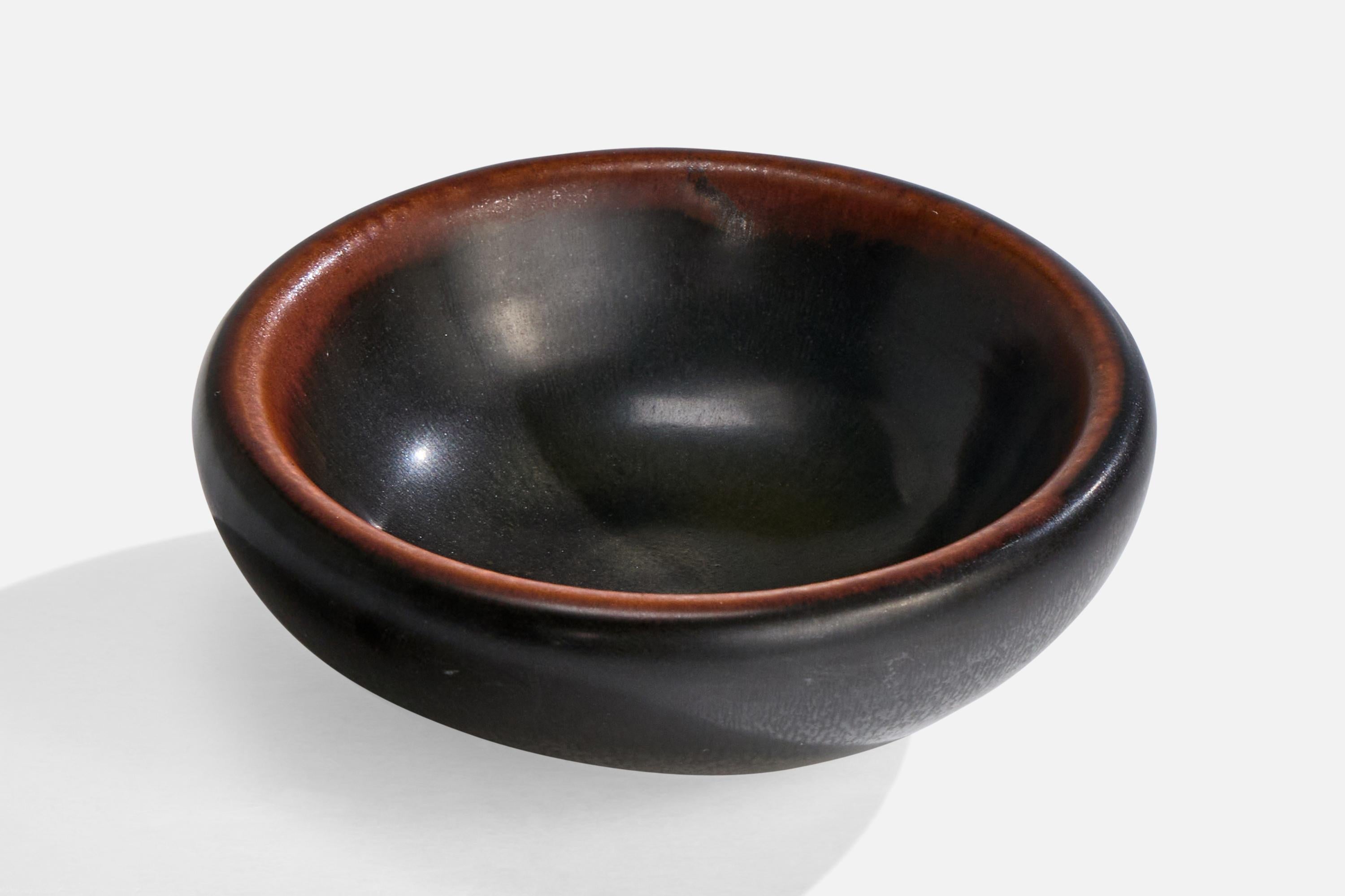 A brown and black-glazed stoneware bowl designed by Gertrud Lönegren and produced by Rörstrand, Sweden, c. 1940s.

Overall Dimensions (inches): 1.5