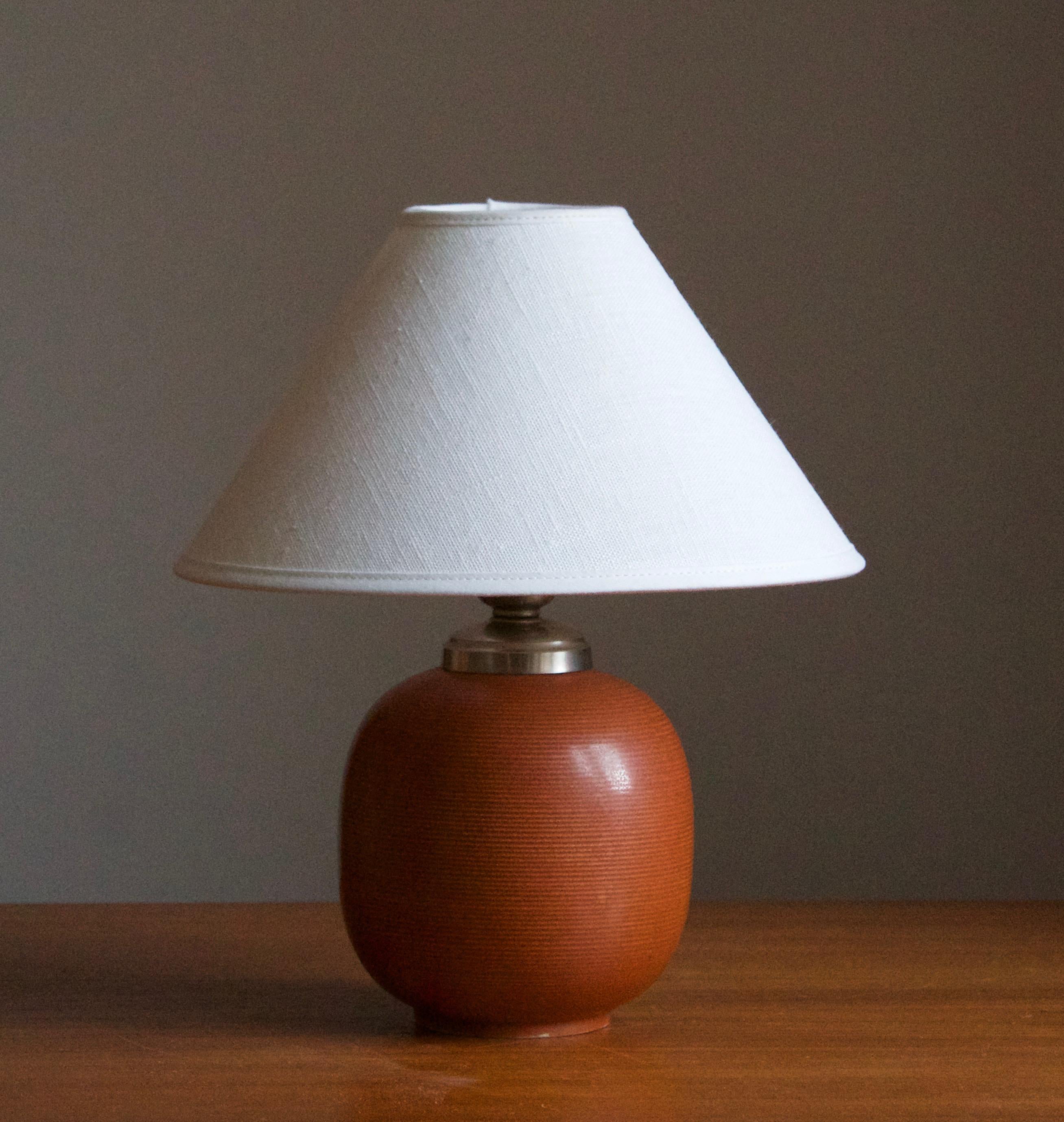 A large and impressive table lamp, designed by Gertrud Lönegren. Produced by Rörstrand. Stamped and with artists initials.

Stated dimensions excluding lampshade. Height includes socket. Sold without lampshade.

Glaze features an orange-brown