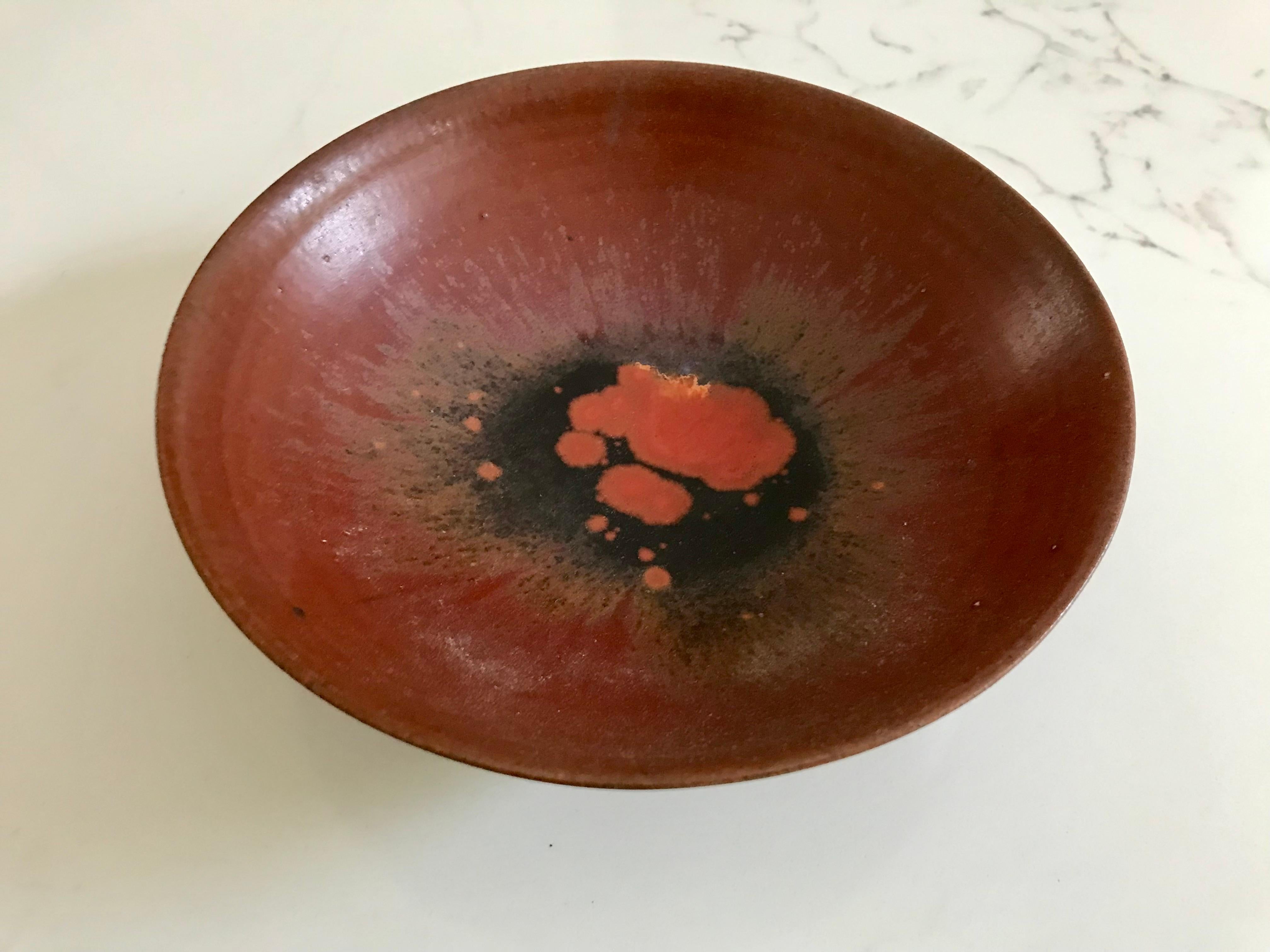 A great piece of California modern design.
By the husband + wife duo G + O Natzler. 
She threw the pottery on a wheel and he mixed the amazing glazes.
Rare footed bowl.
Thin walled clay.
Beautiful oxblood color with other hues that bleed