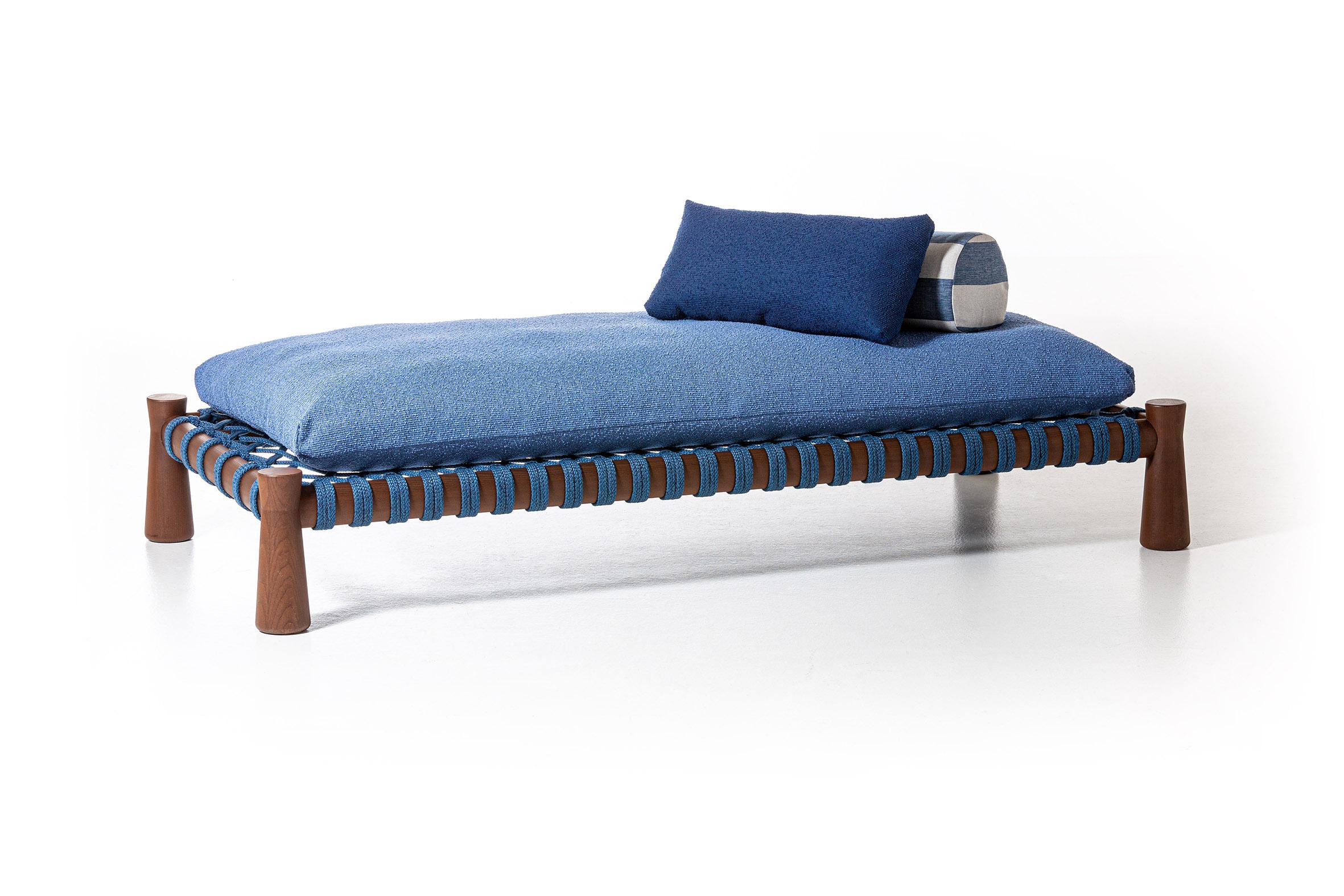 Das Charpoy, ein traditionelles, niedriges und geräumiges indisches Bett, wird von Chiara Andreatti durch die Verwendung von Seilen in den Farben Natur, Rot und Blau neu interpretiert, die von Hand in die Struktur aus für den Außenbereich