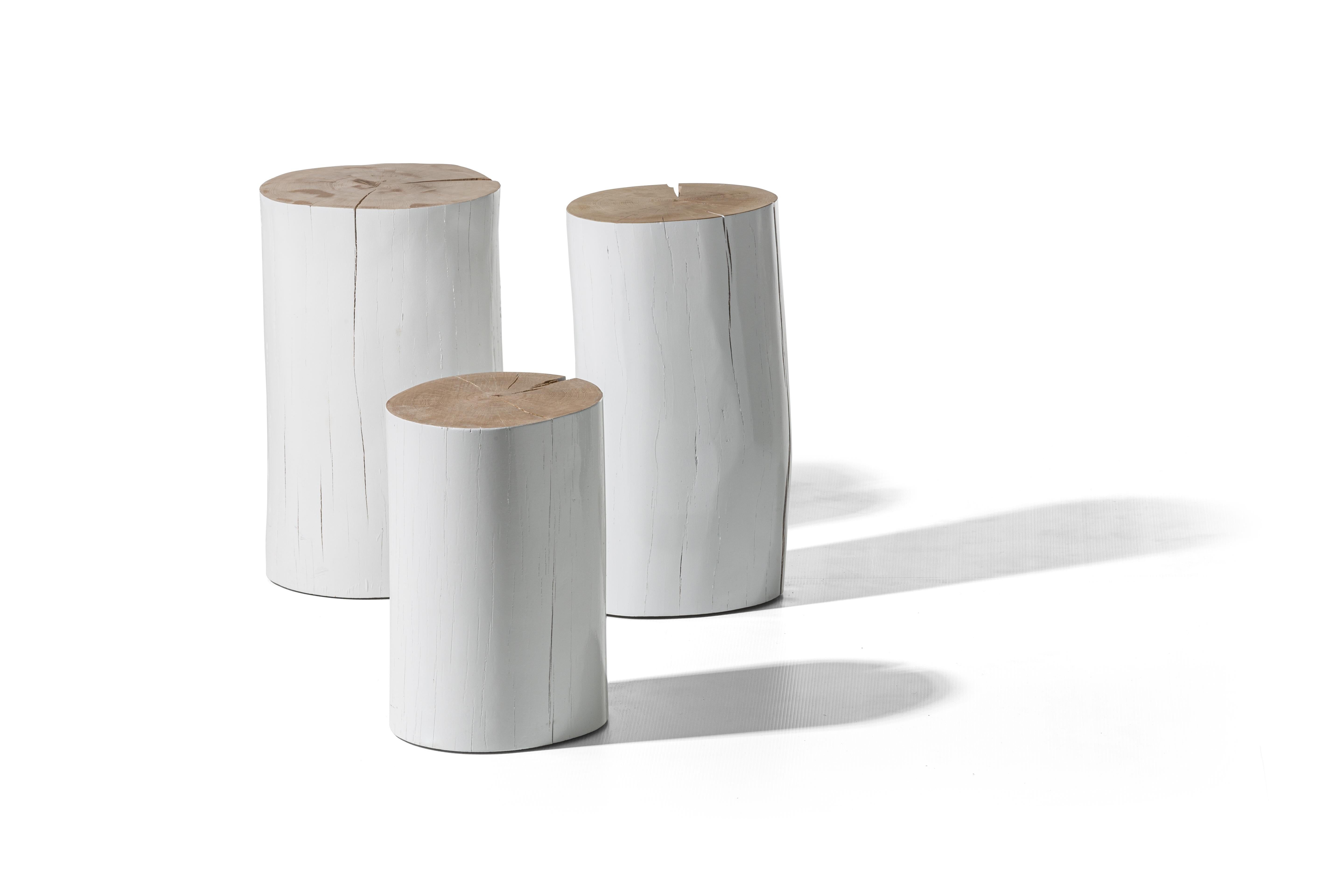 Sections of beech trunk, debarked and glossy black or white lacquered on the outside, give life to a family of unconventional coffee tables and poufs, offering a natural charm to any interior. In the characteristic cylinder shape of a trunk, they