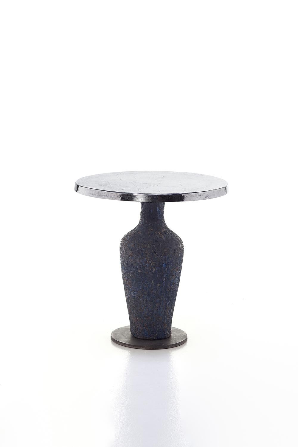 Une combinaison audacieuse de matériaux caractérise la famille de tables Moon 39/40/42 : disponibles en différentes tailles, elles ont une base en céramique bleue en forme d'amphore, plus ou moins allongée selon la hauteur du produit, caractérisée