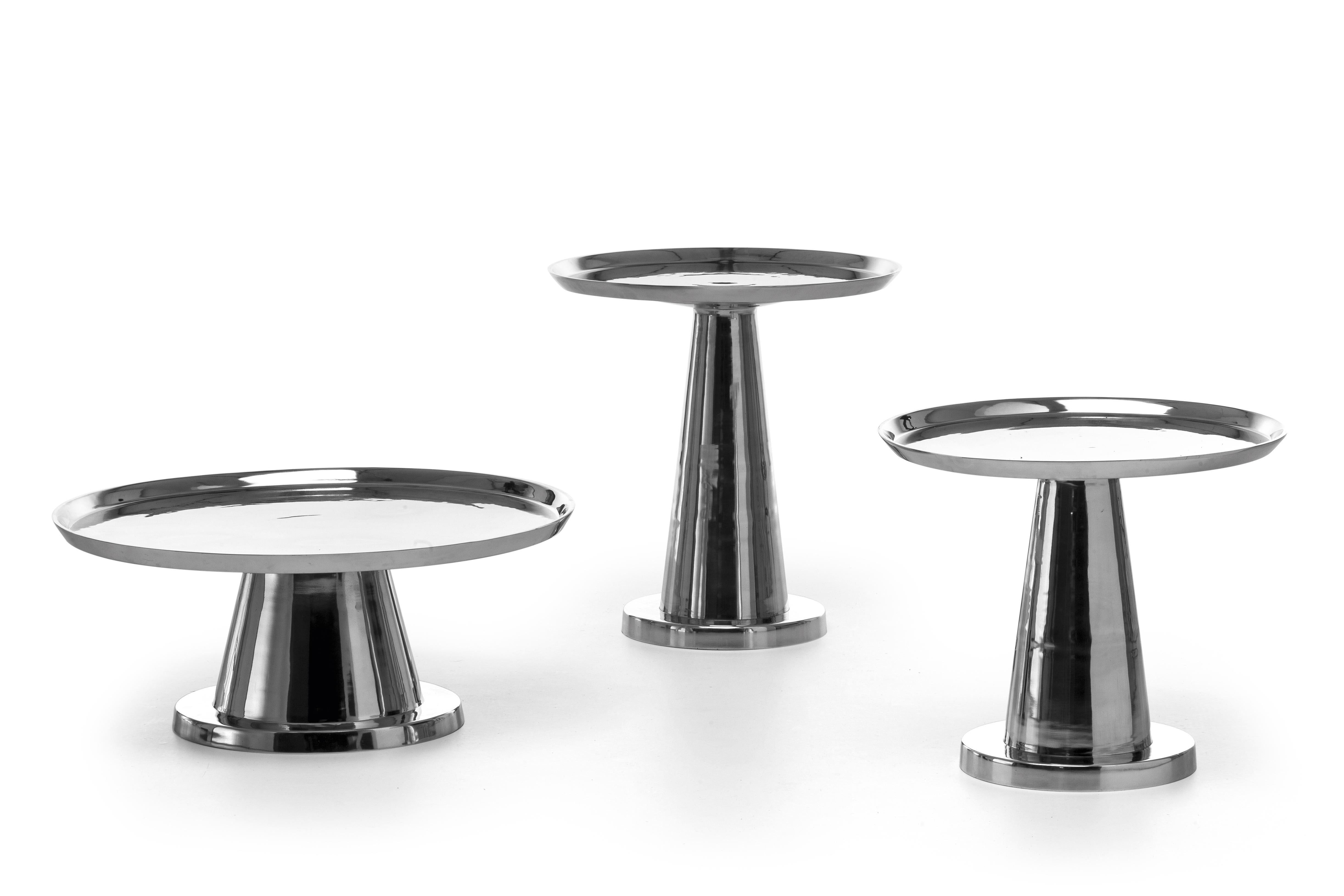 Contrasts of light and reflections characterise the Next 141/142/144 coffee table family. Made entirely of polished cast aluminium, they are available in different sizes and heights and are characterised by a single central base that seems to