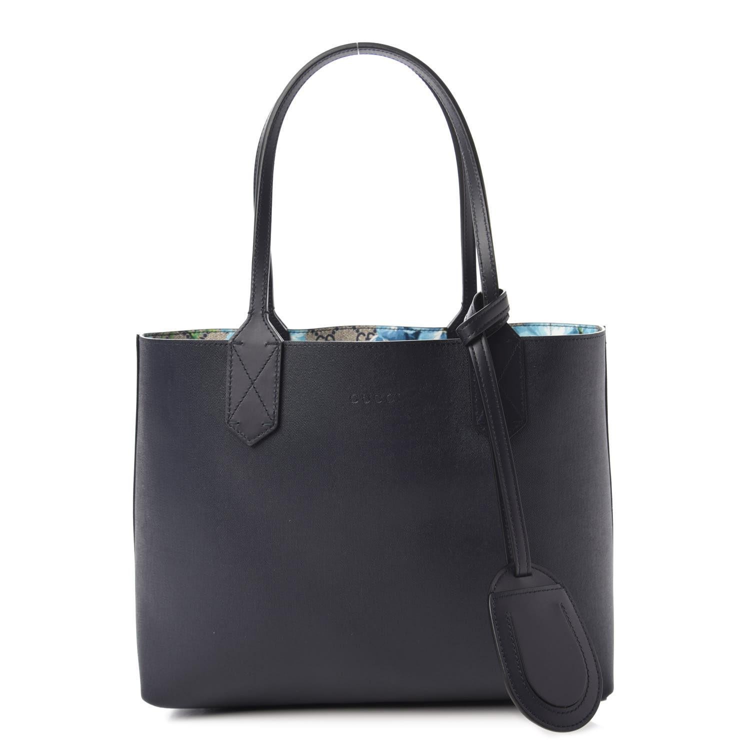 This tote is made withI GG Supreme Monogram canvas with blue and white blooming Flowers. The bag features very tall dark blue dual flat leather strap top handles. The handbag has a broad opening to a dark blue coated canvas interior that can be