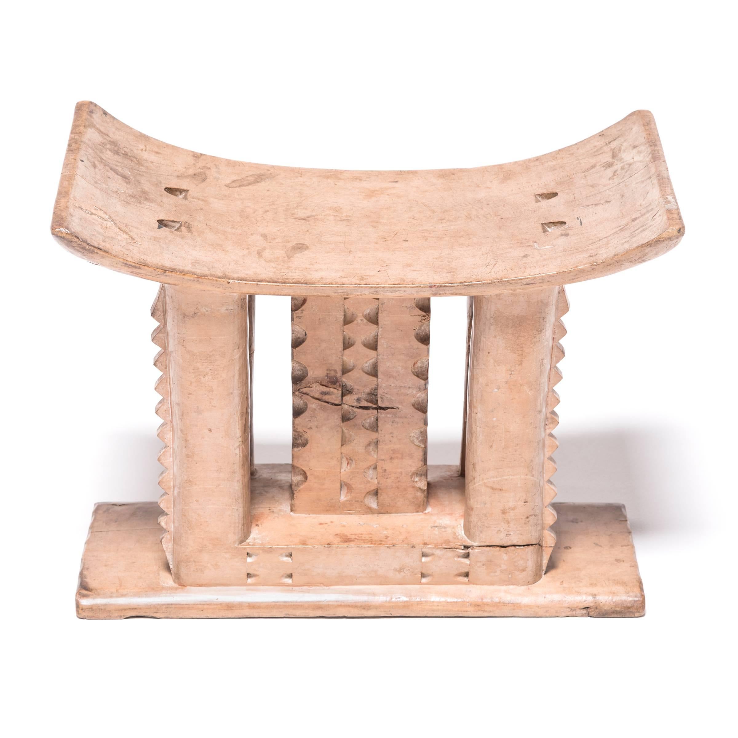 Stools indicated power, status, and lines of succession in traditional Ashanti culture. The flat base, curved seat, and ridged supports reference the Ashanti King stool. While many stools of this type incorporate carvings from the Adinkra symbol