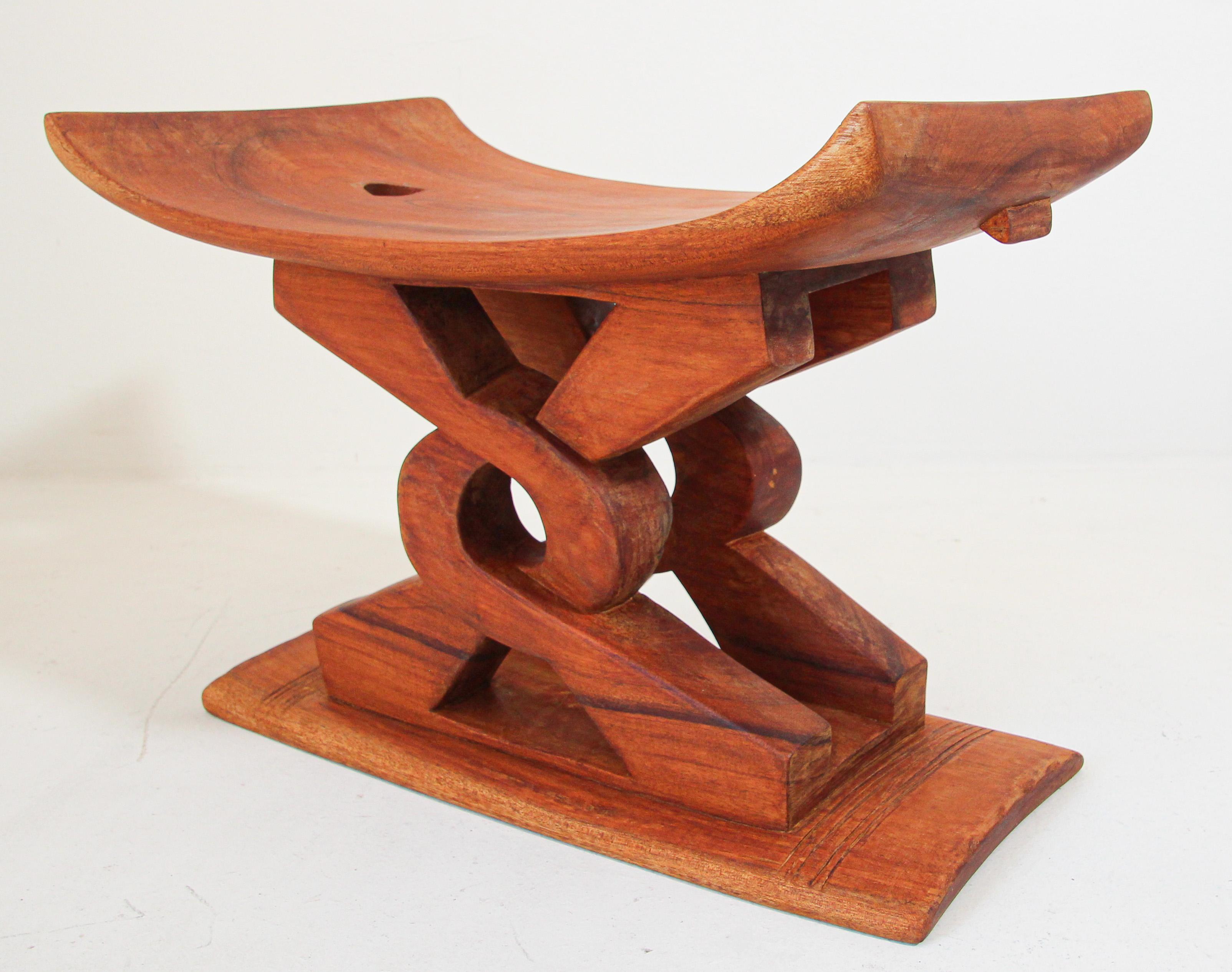 African Tribal handcrafted Ghanaian Ashanti 'Wisdom Knot' Stool Africa.
A carved wooden African stool having a curved seat raised on two carved intertwined wooden supports with a slim plinth base. 
Ghanaian lore explains that the central symbol