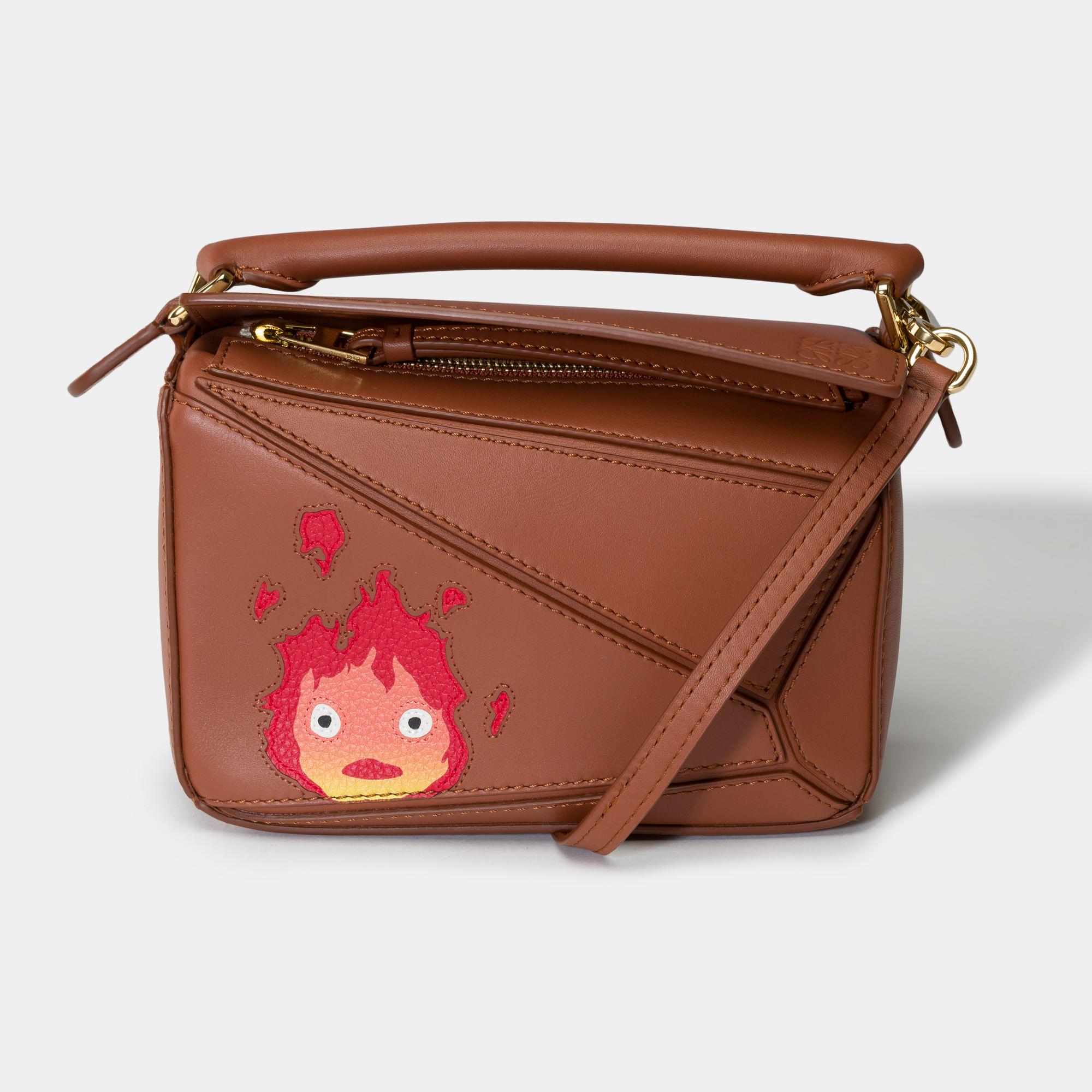 Loewe​ ​Puzzle​ ​Small​ ​bag​ ​limited​ ​edition​ ​in​ ​collaboration​ ​with​ ​Studio​ ​Ghibli​ ​in​ ​caramel​ ​calfskin​ ​with​ ​Calcifer​ ​color​ ​design,​ ​gold​ ​metal​ ​trim,​ ​short​ ​handle​ ​and​ ​removable​ ​adjustable​ ​shoulder​ ​strap​