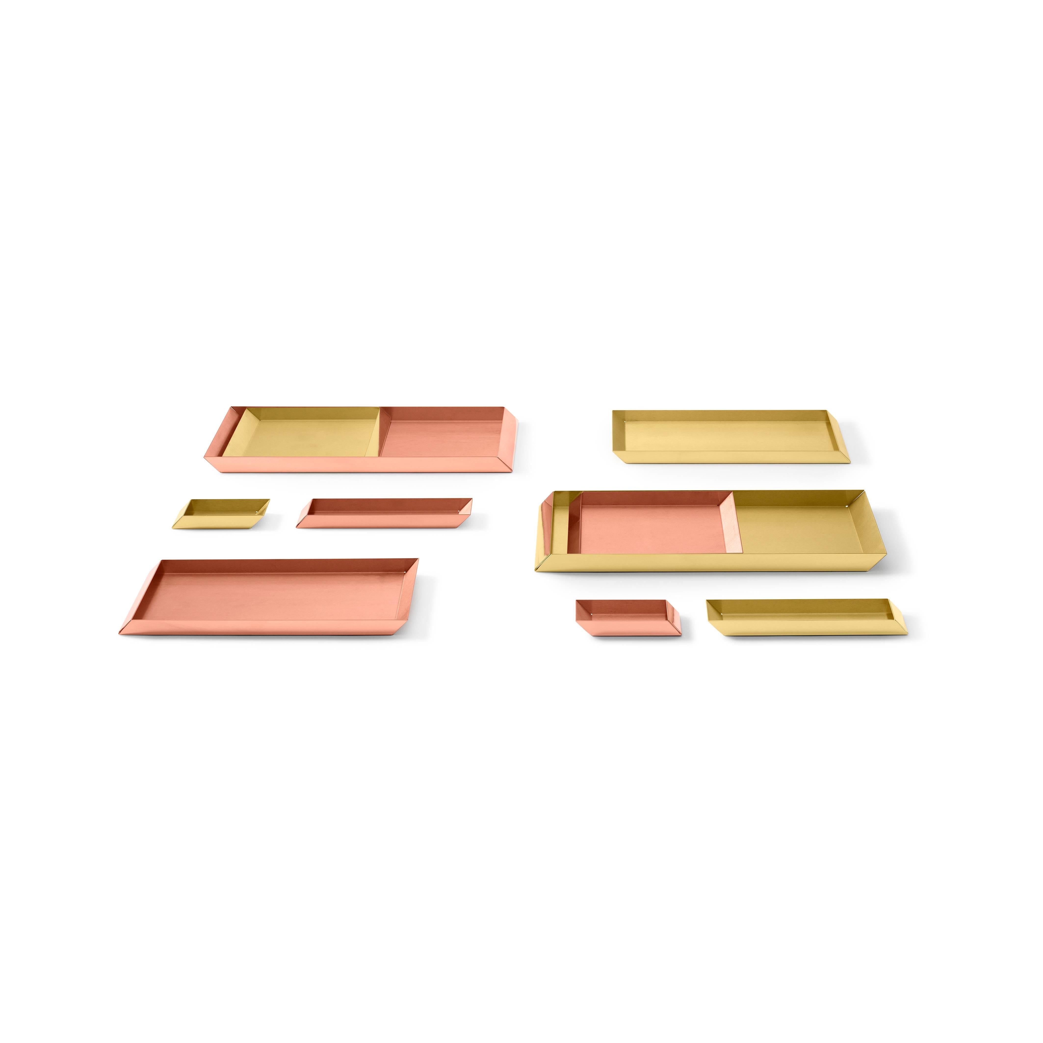 Trays in polished brass. The compositional scheme of this family of small trays is the axonometric isometric projection of two parallelepipeds which creates a three-dimensional optical effect implemented by inclined edges and by contrasting metal