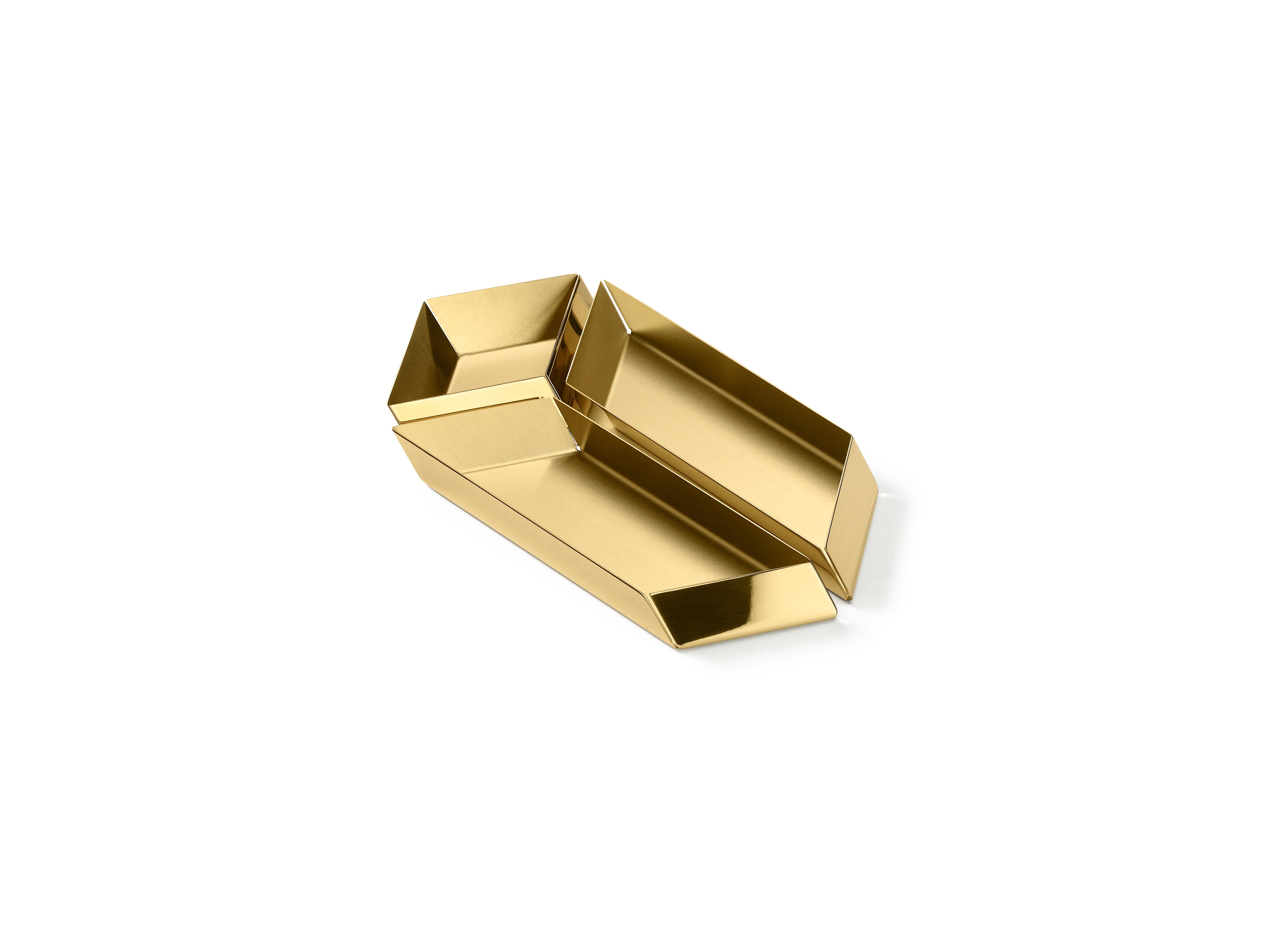 The compositional scheme of this family of small trays is the axonometric isometric projection of two parallelepipeds which creates a three-dimensional optical effect implemented by inclined edges and by contrasting metal finishes. Like in a game,