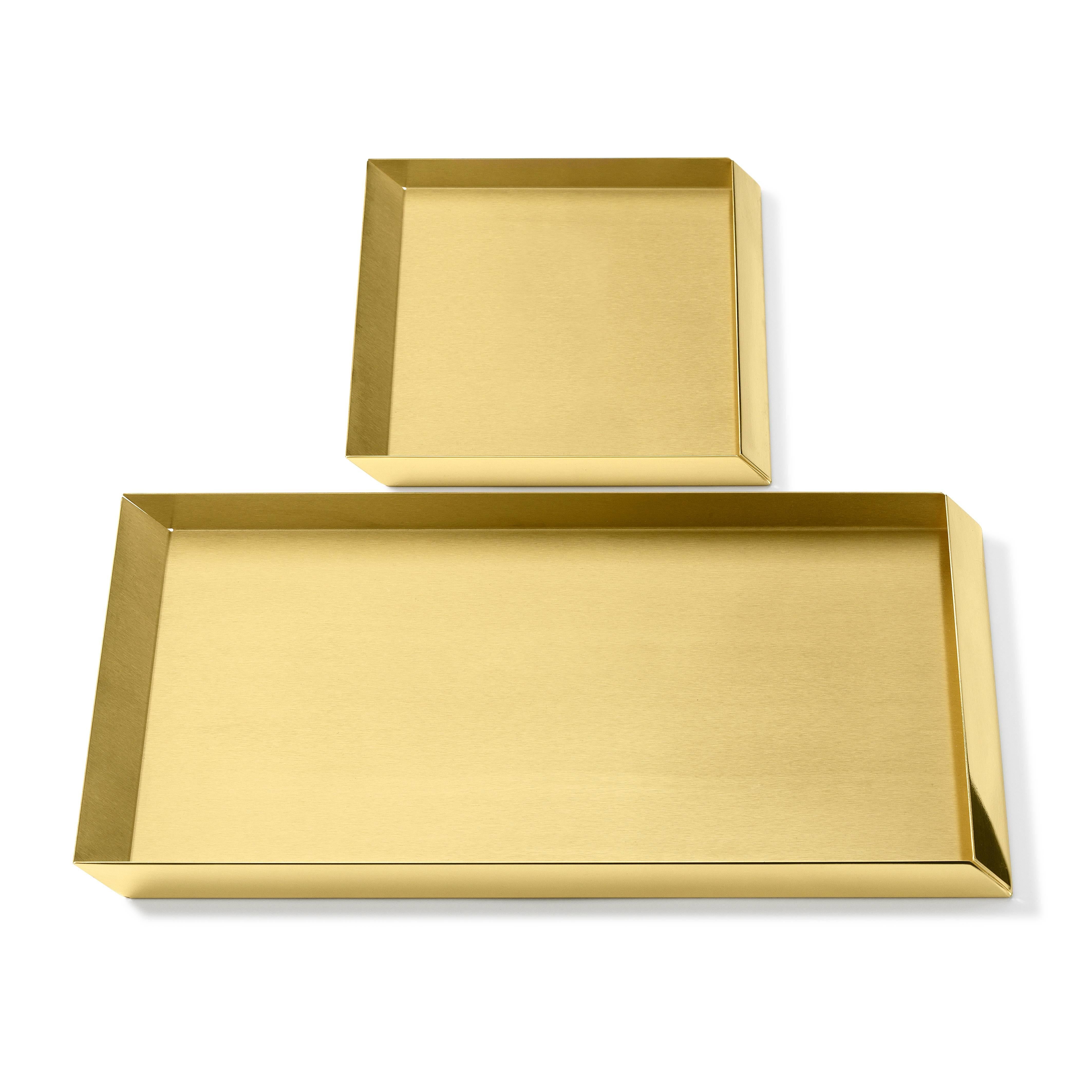 Trays in brass. The compositional scheme of this family of small trays is the axonometric isometric projection of two parallelepipeds which creates a three-dimensional optical effect implemented by inclined edges and by contrasting metal finishes.