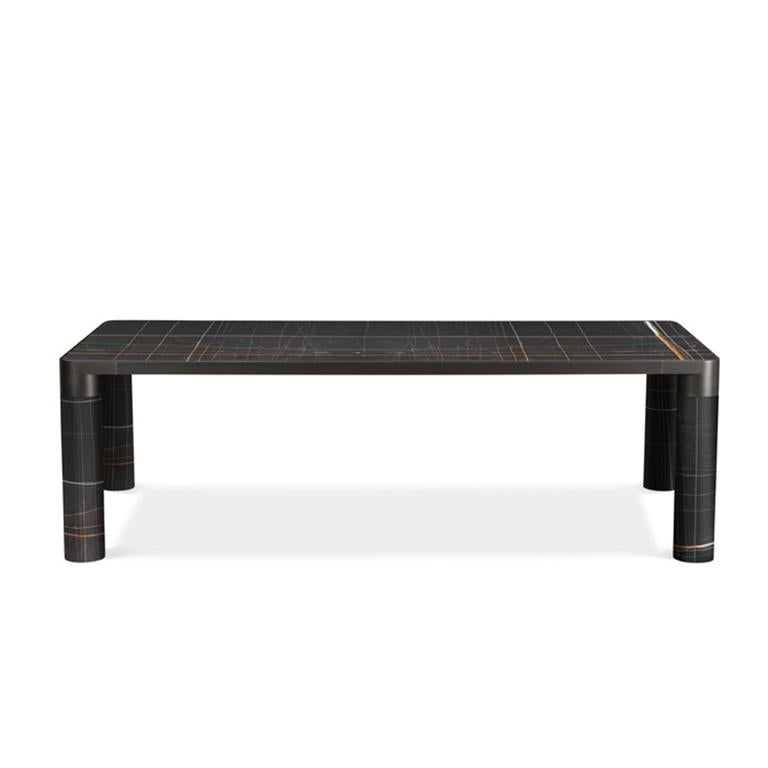 Cette famille de produits fait une déclaration audacieuse avec son pied cylindrique généreux, reliant son périmètre structurel tout en délimitant les objets qui la composent. La bordure métallique distinctive qui soutient les sièges, les tables, les