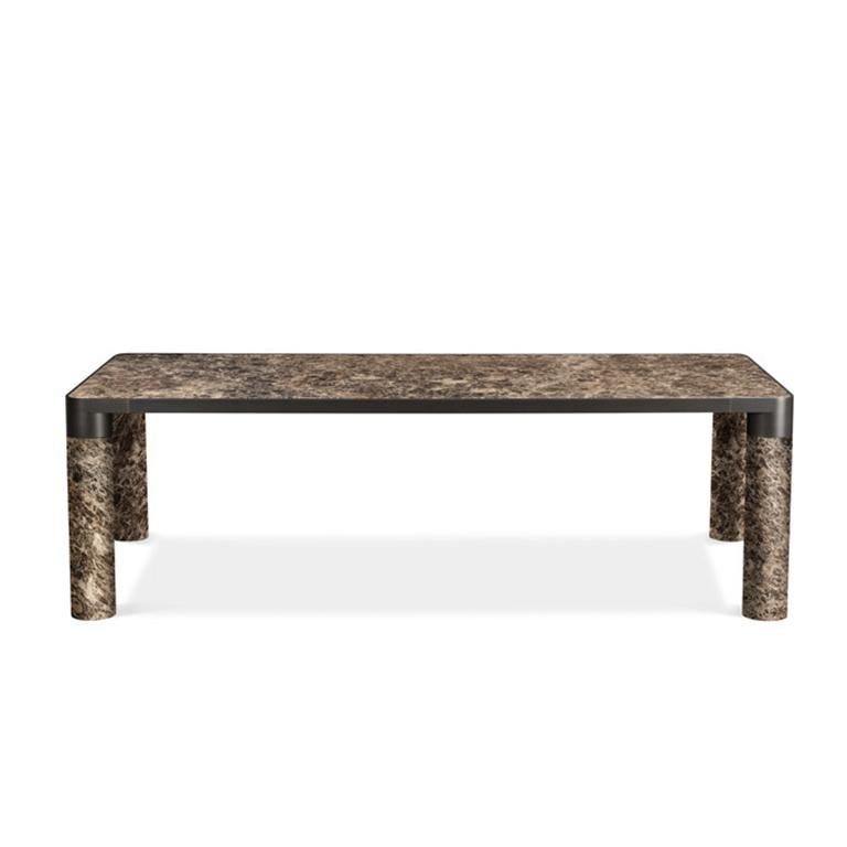 Cette famille de produits fait une déclaration audacieuse avec son pied cylindrique généreux, reliant son périmètre structurel tout en délimitant les objets qui la composent. La bordure métallique distinctive qui soutient les sièges, les tables, les