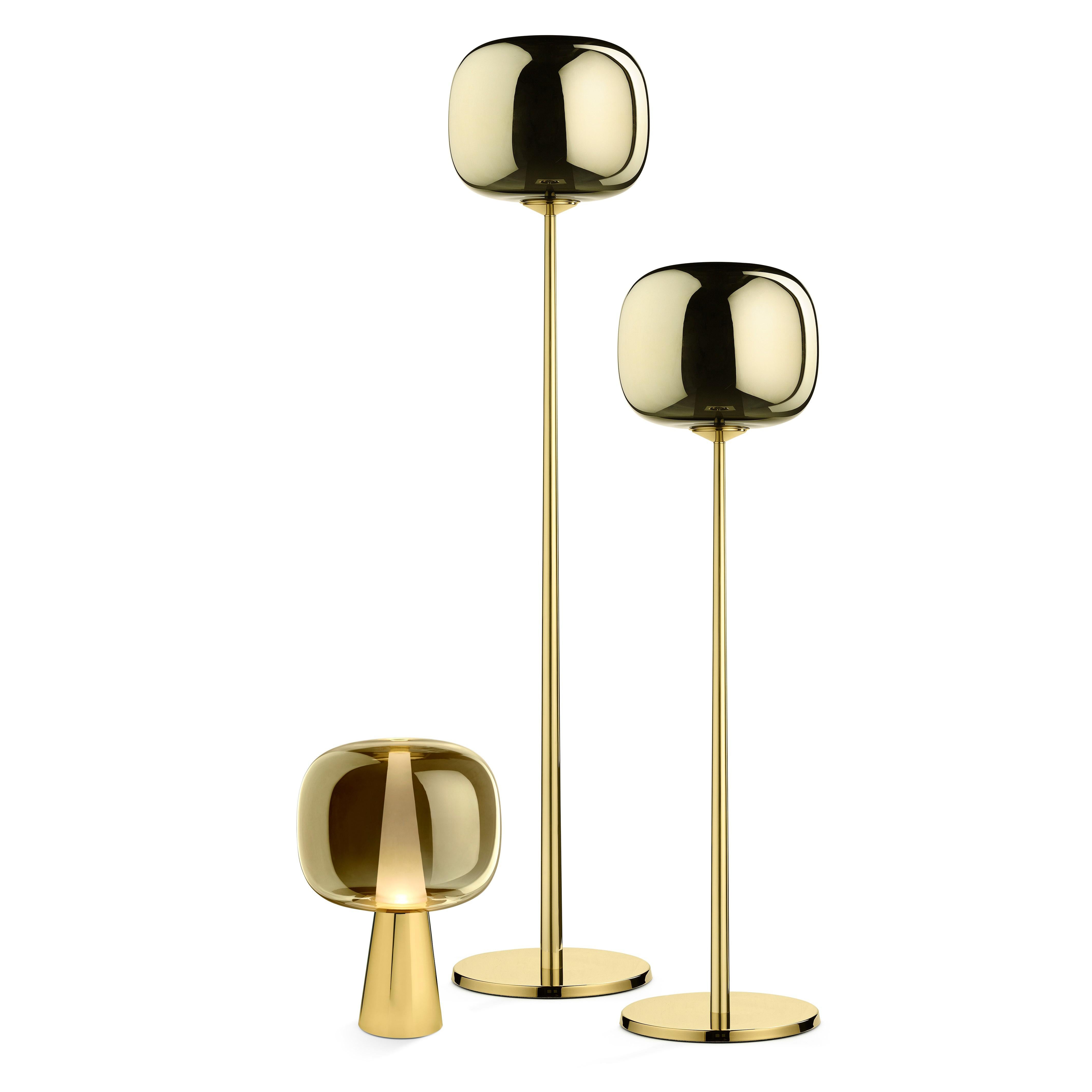Floor lamp in brass and metalized glass. Dusk Dawn draws its name from a magical arc of time: the arrival and departure of soft light. It is the time when the sun dips below the horizon to leave an afterglow that signals the arrival of the night,