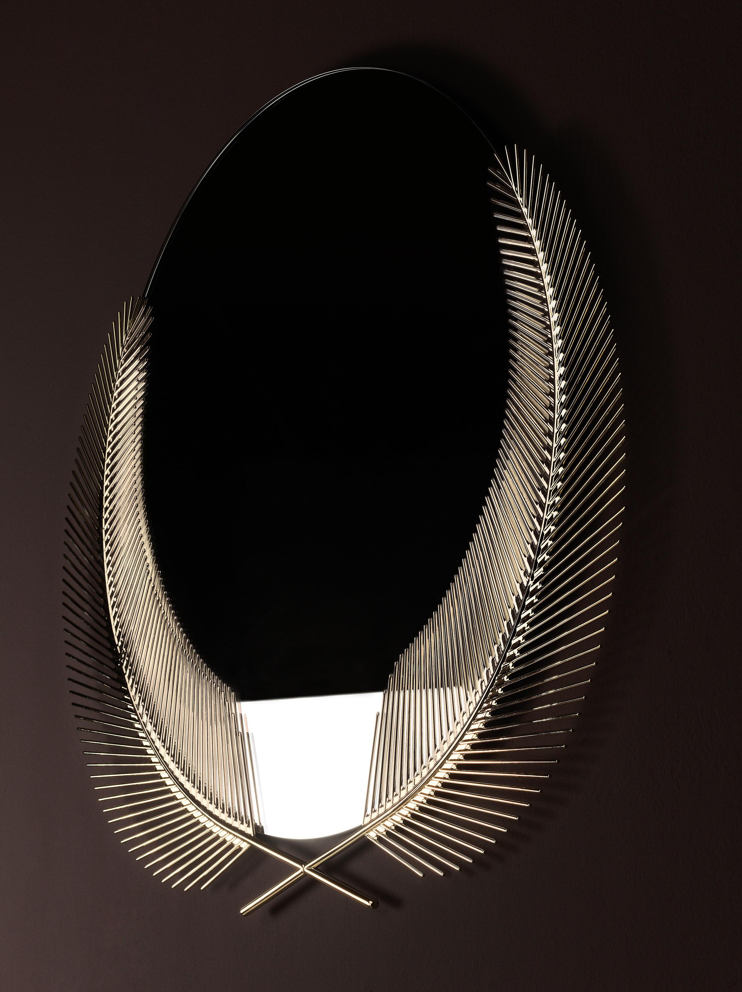 Mirror with palm leaves in brass. The round mirror surface is sunk into the graphic embrace of two palm fronds. The Sunset mirror is wall-mounted declaration of the true summer paradise scenario that lingers just below the surface of the present