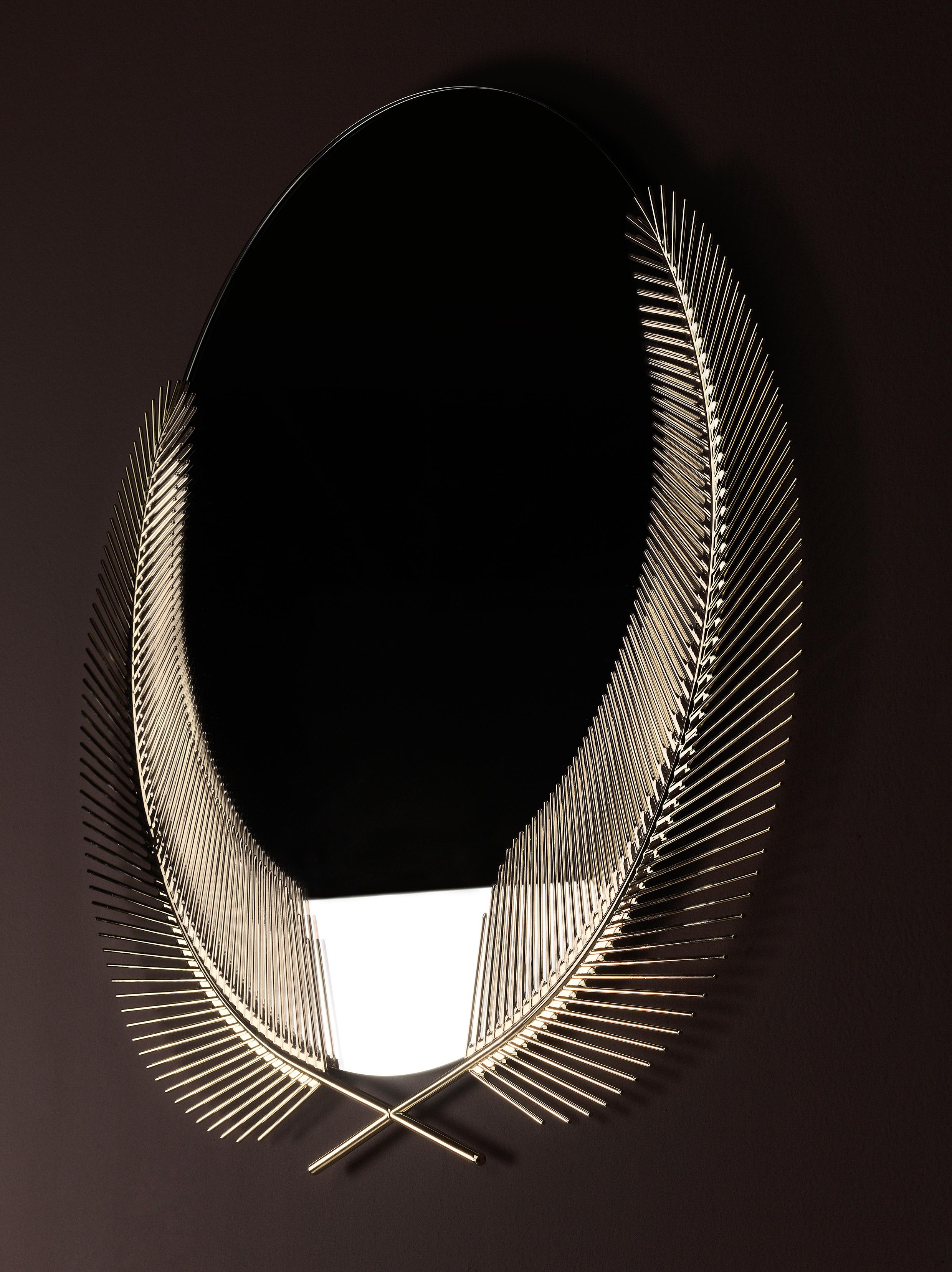 Mirror with palm leaves in brass. The round mirror surface is sunk into the graphic embrace of two palm fronds. The Sunset mirror is a wall-mounted declaration of the true summer paradise scenario that lingers just below the surface of the present