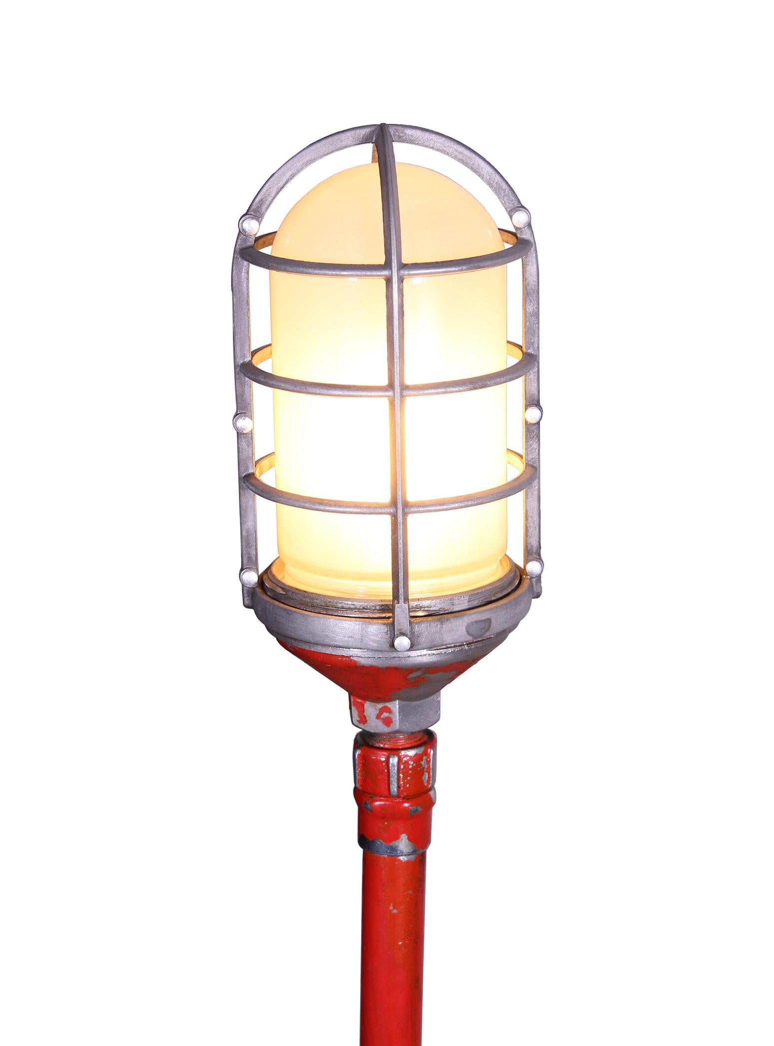 Vintage industrial, Gothic, theater stage floor lamp, ghost light, made with an explosion proof bulb housing, steel pole and cast iron stand. Fitted with Edison bulb. Distressed faded red paint.