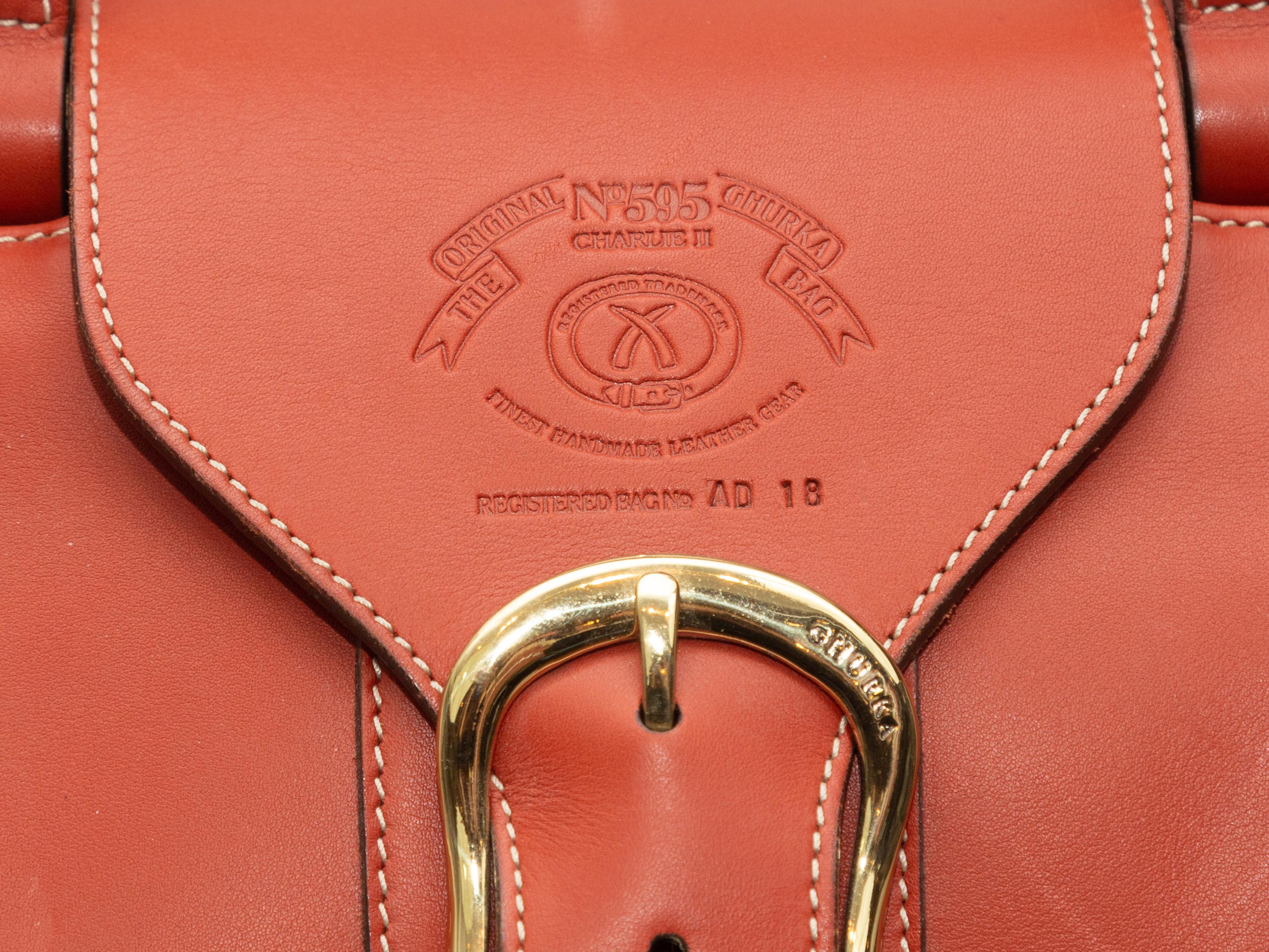 Product details: Orange large leather handbag by Ghurka. Interior zip pocket. Wooden detailing at dual top handles. Buckle closure at top. 15