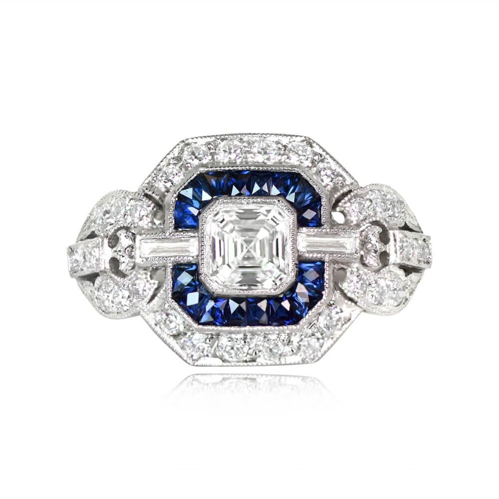 A mesmerizing Asscher cut diamond and sapphire engagement ring captivates the eye. The center Asscher cut diamond, certified by GIA at 0.50 carats, showcases J color and VS1 clarity. It is elegantly accompanied by two baguette-cut diamonds.