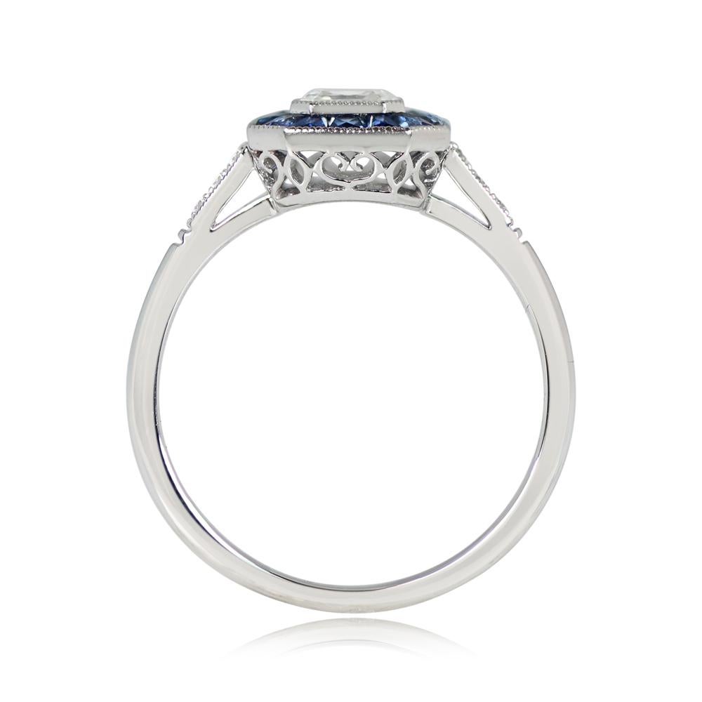 A modern geometric engagement ring with a 0.50-carat asscher cut diamond at the center, GIA-certified as J color and VS1 clarity. The diamond is encircled by a row of French-cut natural sapphires. This platinum ring has a sleek profile, and an