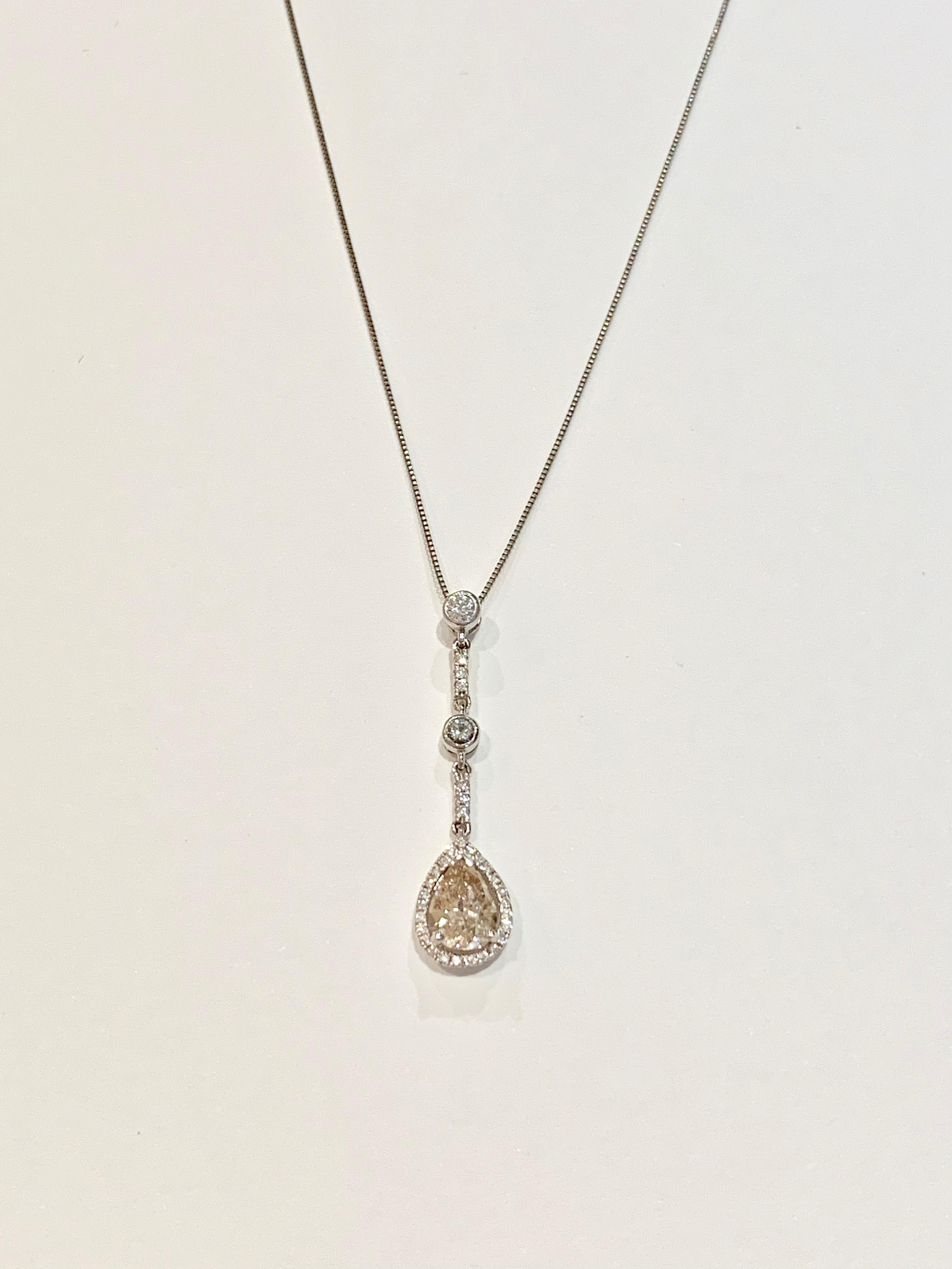 This very elegant drop pendant is made up of a GIA Certified 0.83ct Fancy Yellow/Brown* Pear Cut Diamond set in a diamond halo surround and suspended from a diamond set jointed bale.  The pendant setting contains 0.19ct of round brilliant cut stones