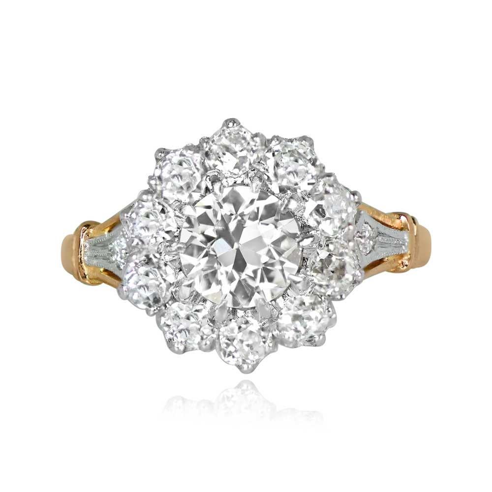 A stunning cluster engagement ring showcases a lively GIA-certified 0.84-carat old European cut diamond, surrounded by a floral halo and adorned with additional diamonds. The fleur de lis design on each shoulder adds an extra touch of elegance.