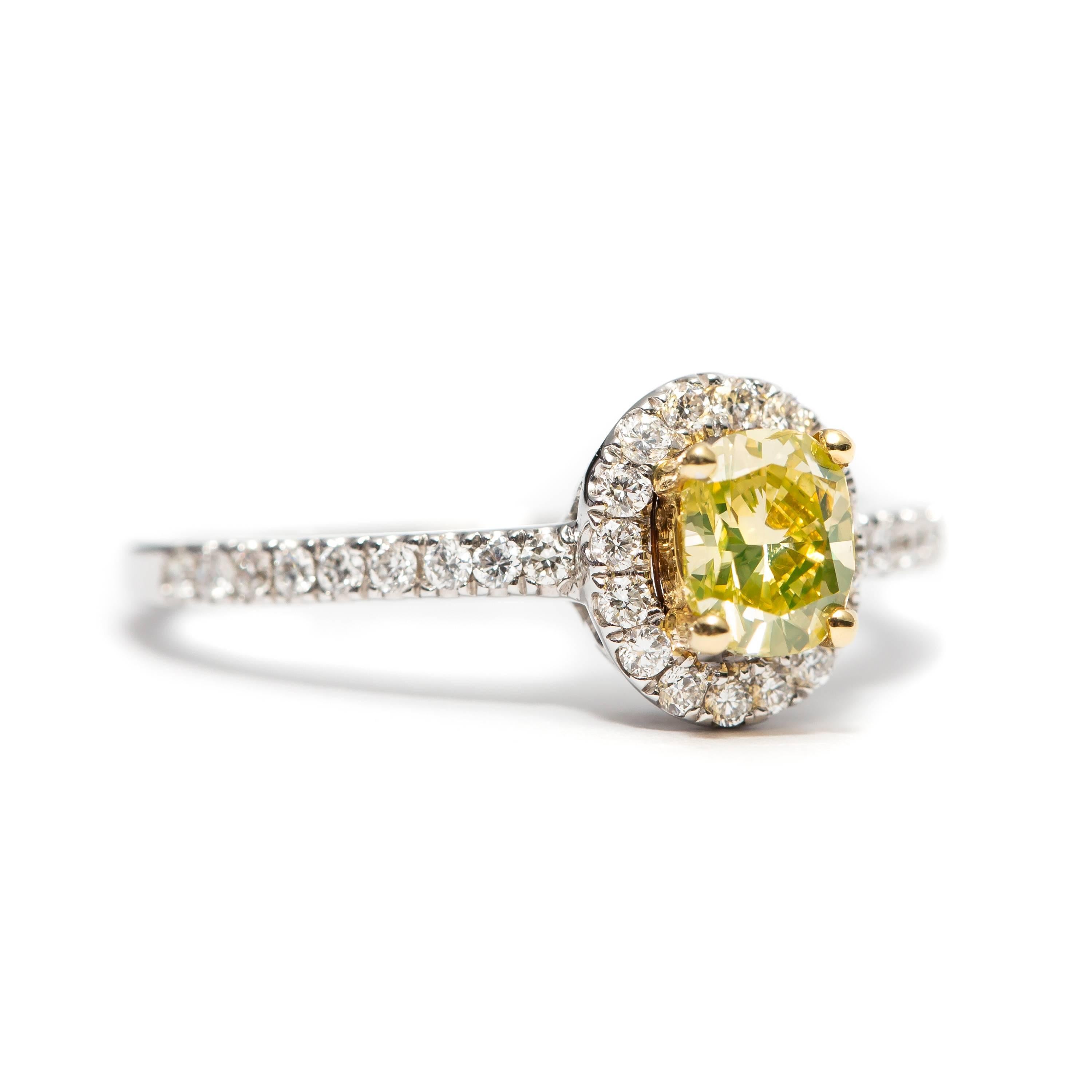 Ce superbe diamant certifié GIA de 0,52 carat, de couleur naturelle jaune fantaisie et de taille coussin, est serti au centre du halo, tandis que 0,35 carat de diamants ronds brillants de couleur G et de pureté VS entourent le halo et les épaules de