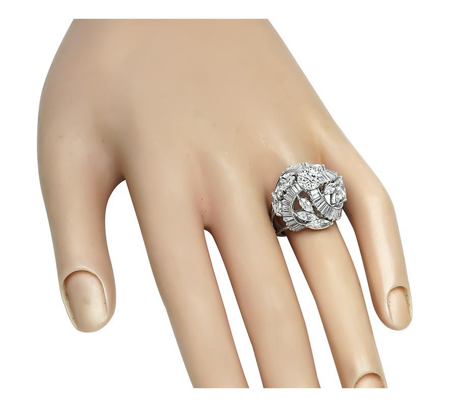 This is an elegant platinum cocktail ring. The ring is centered with sparkling GIA certified round cut diamond that weighs 0.88ct. The color of the diamond is I with VS2 clarity. The center diamond is accentuated by dazzling baguette, round and