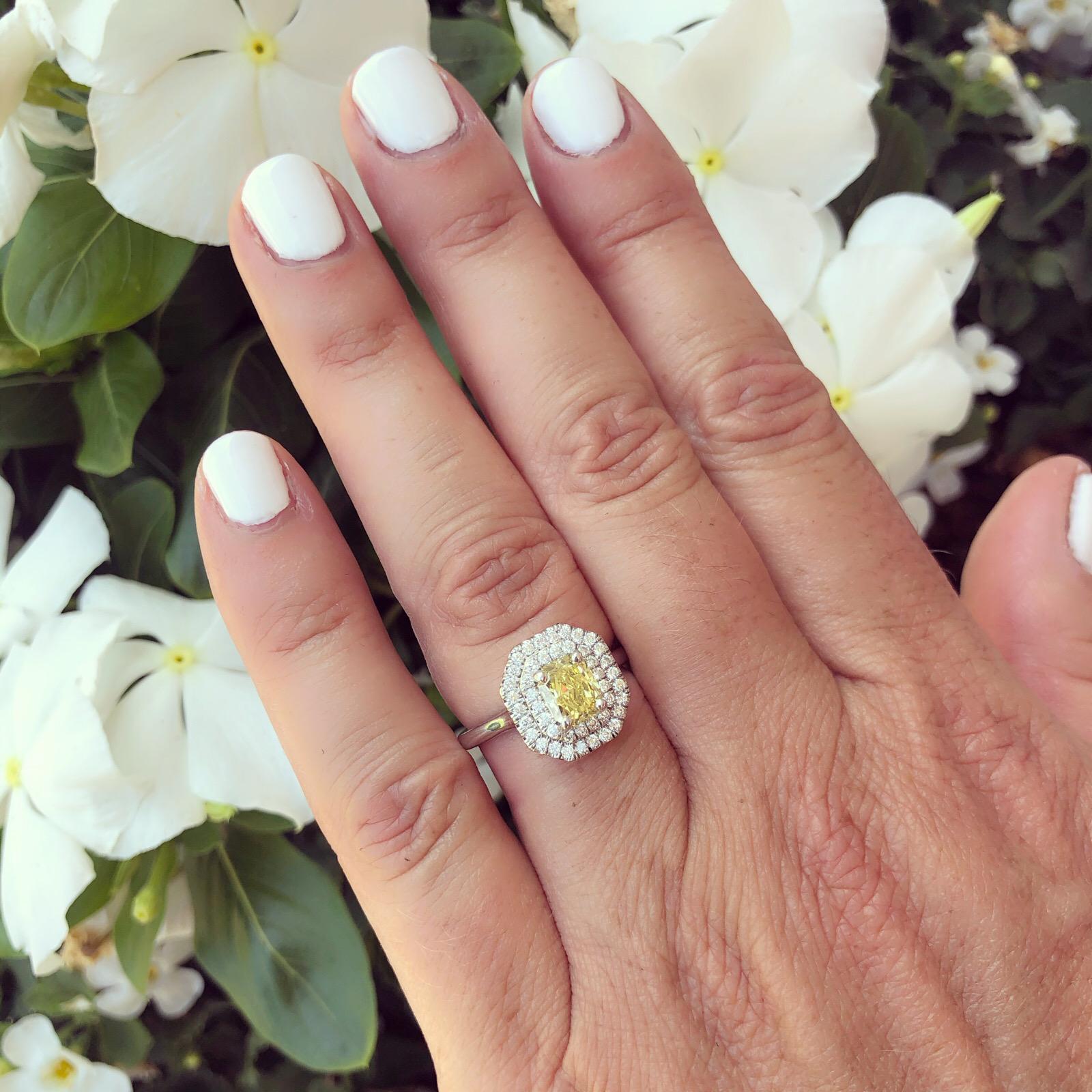 A contemporary and classic designed platinum ring, with a 1.01 carat GIA graded Fancy Intense Yellow/VVS1 radiant-cut diamond, even distribution, framed with a double halo of round brilliant-cut diamonds. Total diamond weight is 1.46 carats. The