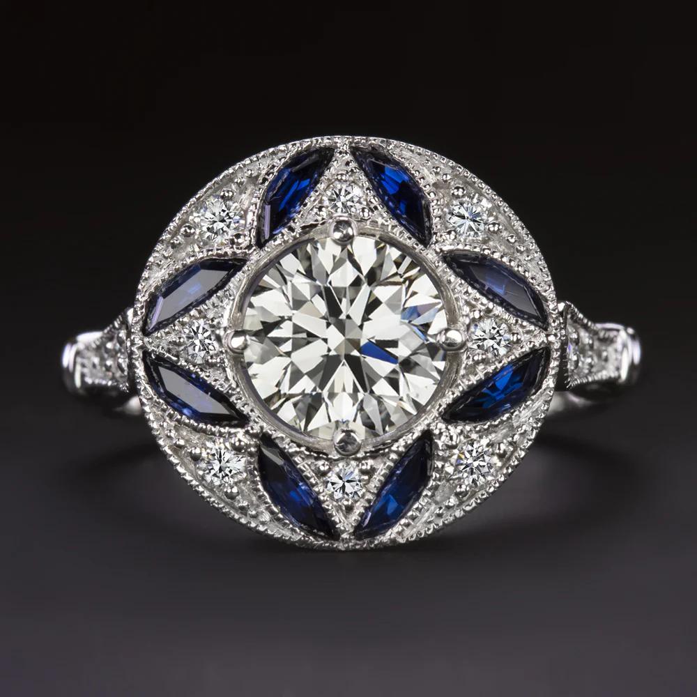 Questo affascinante anello si ispira all'audace geometria dell'epoca Art Deco, con un design circolare perfettamente bilanciato che irradia colore e splendore. Al centro c'è un diamante rotondo taglio brillante da 1,03 carati certificato GIA, di