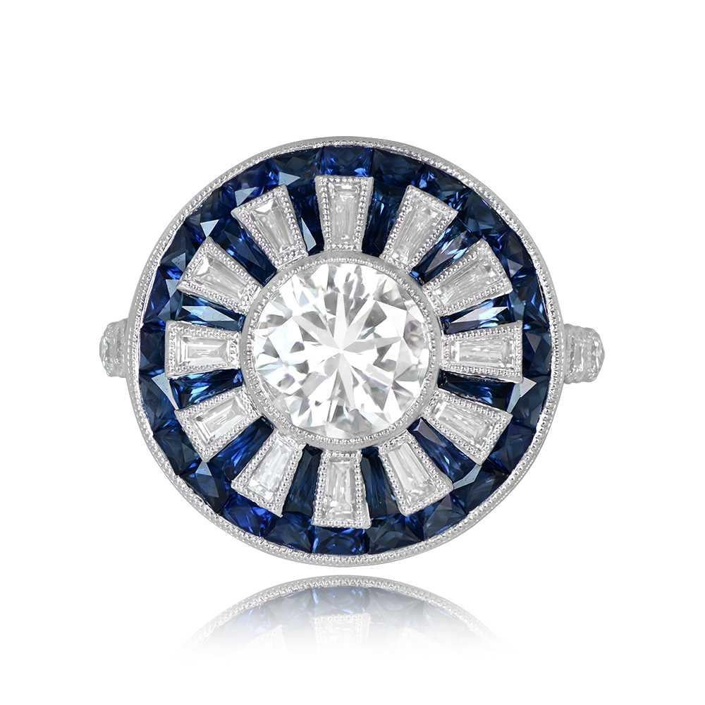 A GIA-certified diamond ring highlights a bezel-set 1.04-carat transitional cut diamond with I color and VS2 clarity. The center diamond is embraced by a halo of tapered baguette diamonds set in bezels, bordered by natural French cut sapphires.