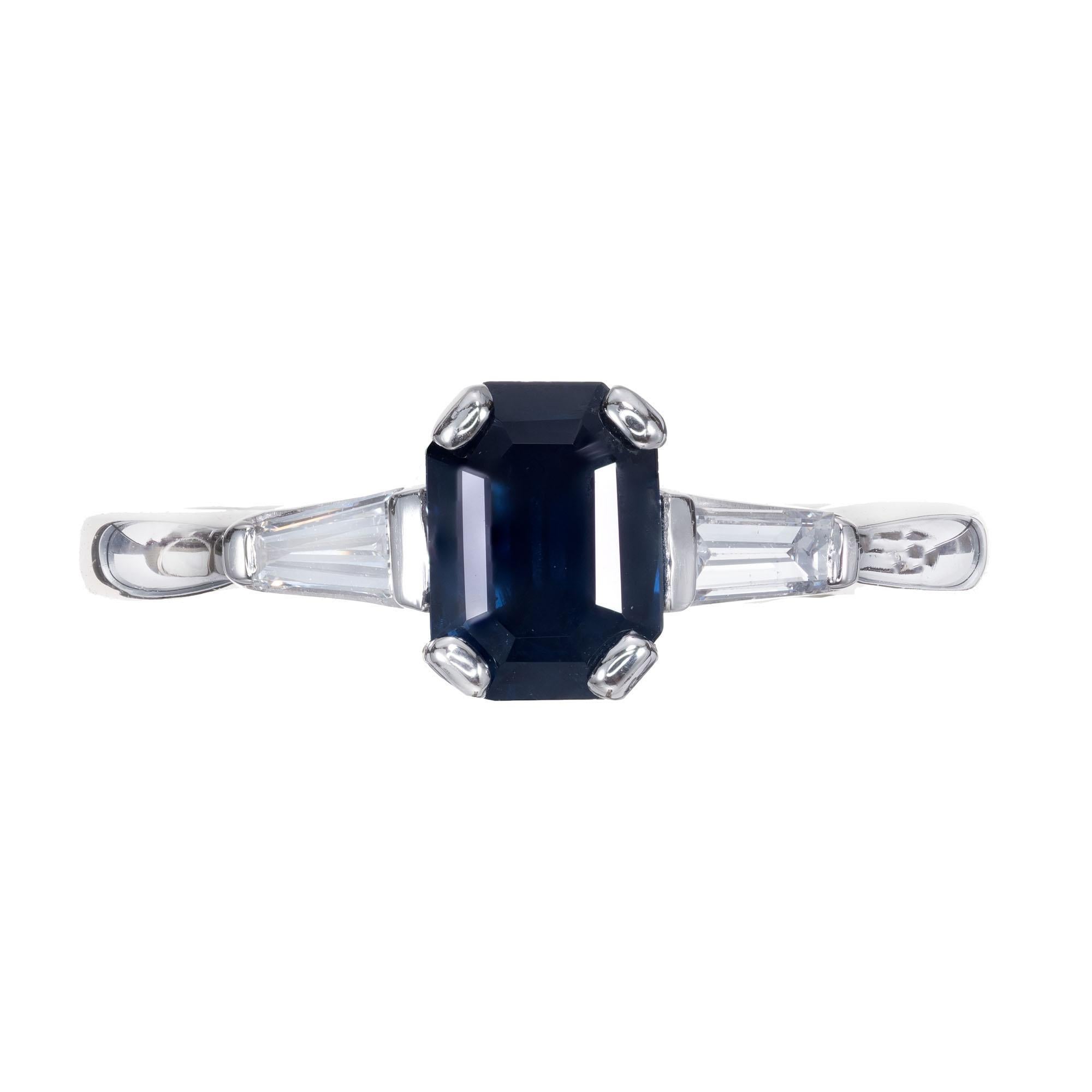 Emerald cut Sapphire and diamond platinum engagement ring. GIA certified center sapphire, with two tapered baguette side diamonds in a platinum three-stone setting. 

1 octagonal step cut dark blue Sapphire, approx. total weight 1.05cts, SI, 6.92 x